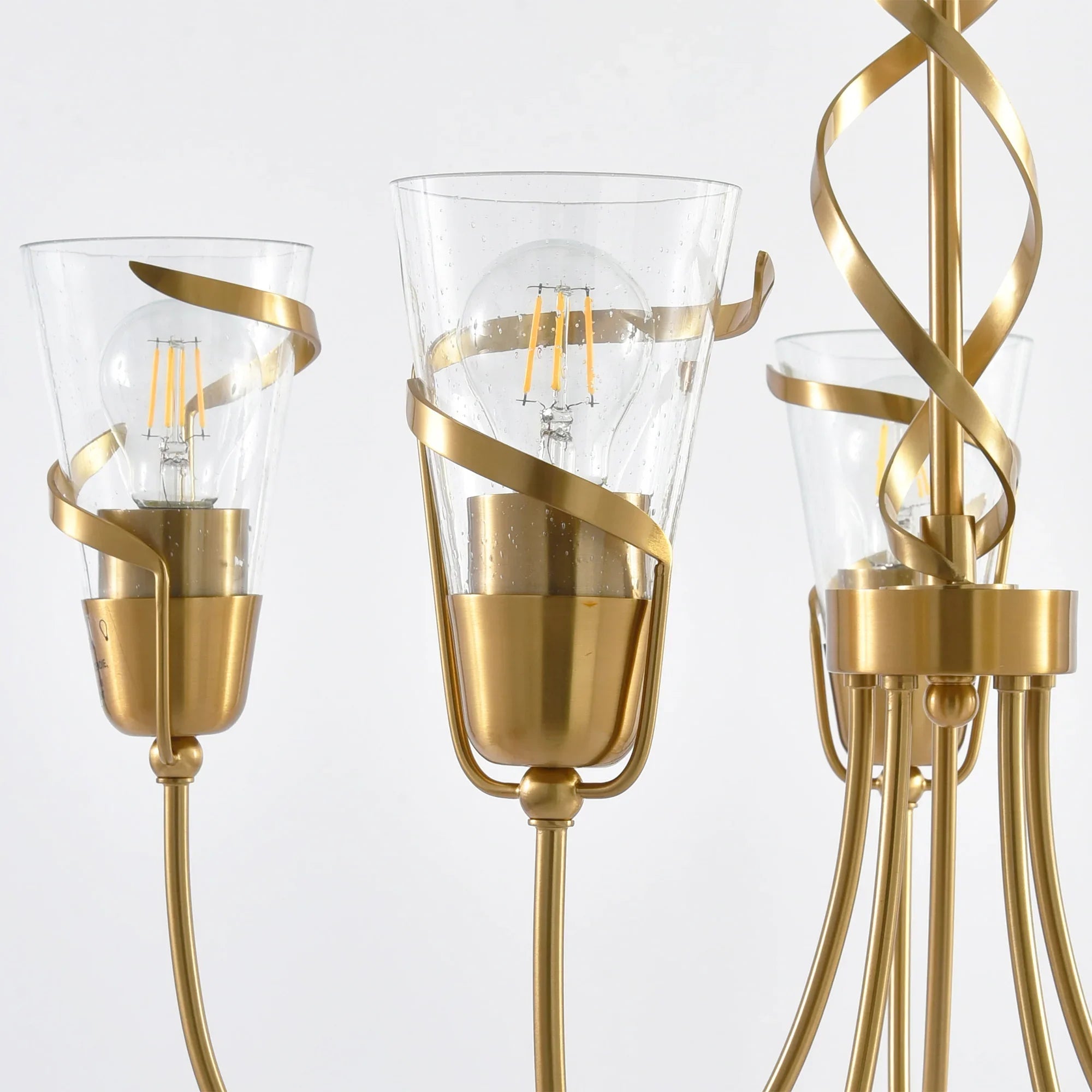Close-up of golden 5-light chandelier with clear glass candle cups and finials