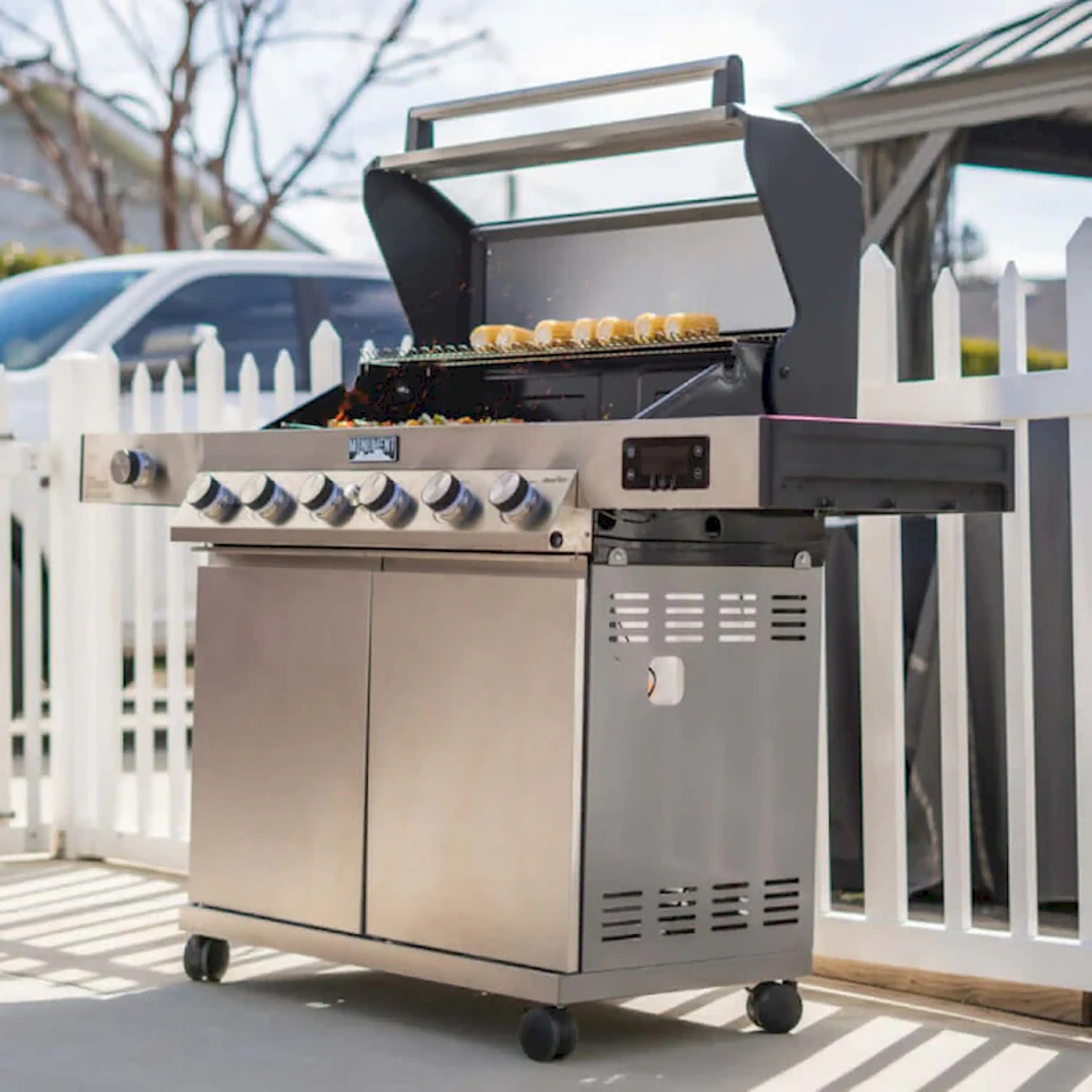 Stainless gas grill cart with open hood, control panel, and side doors