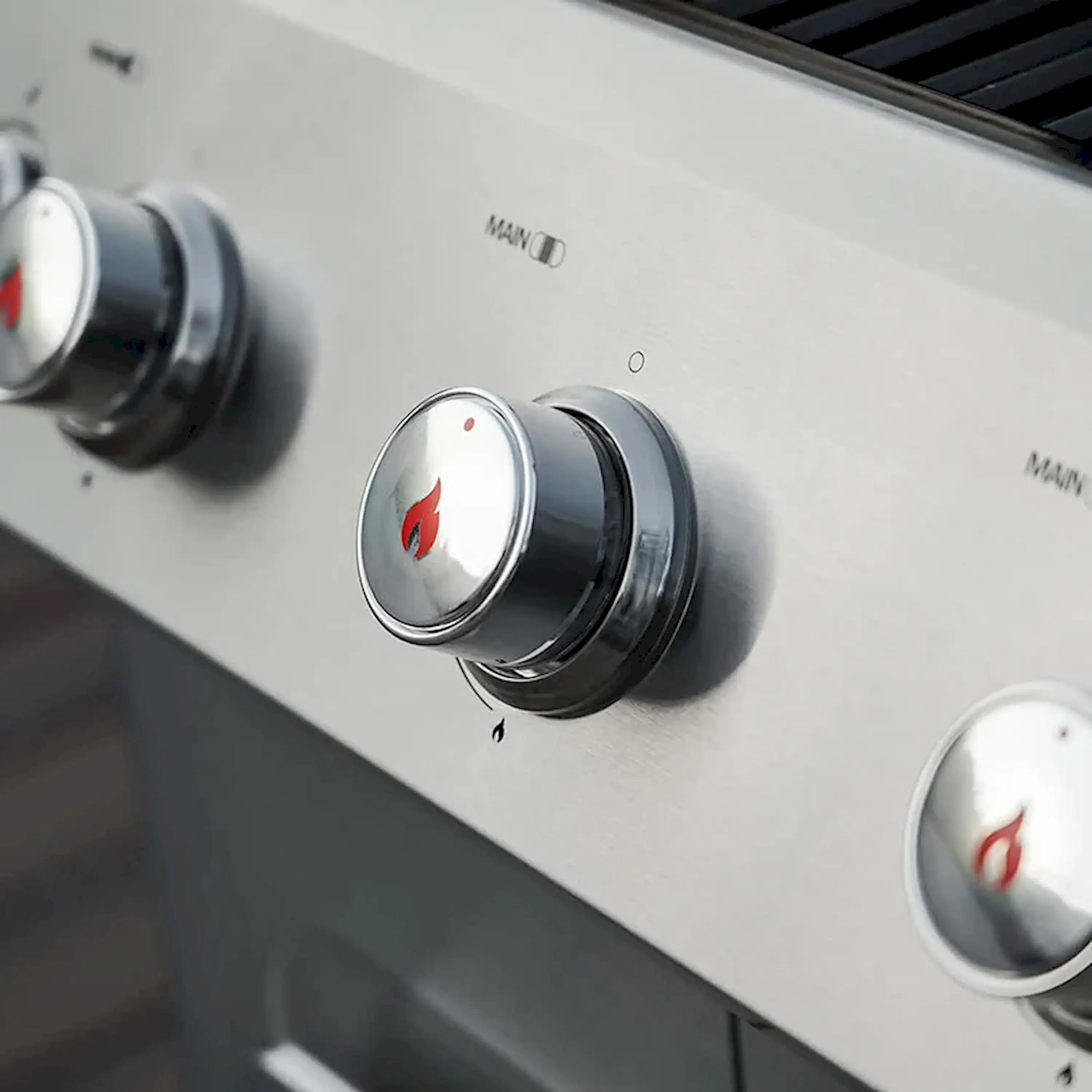Propane grill control knobs with flame indicators on stainless control panel