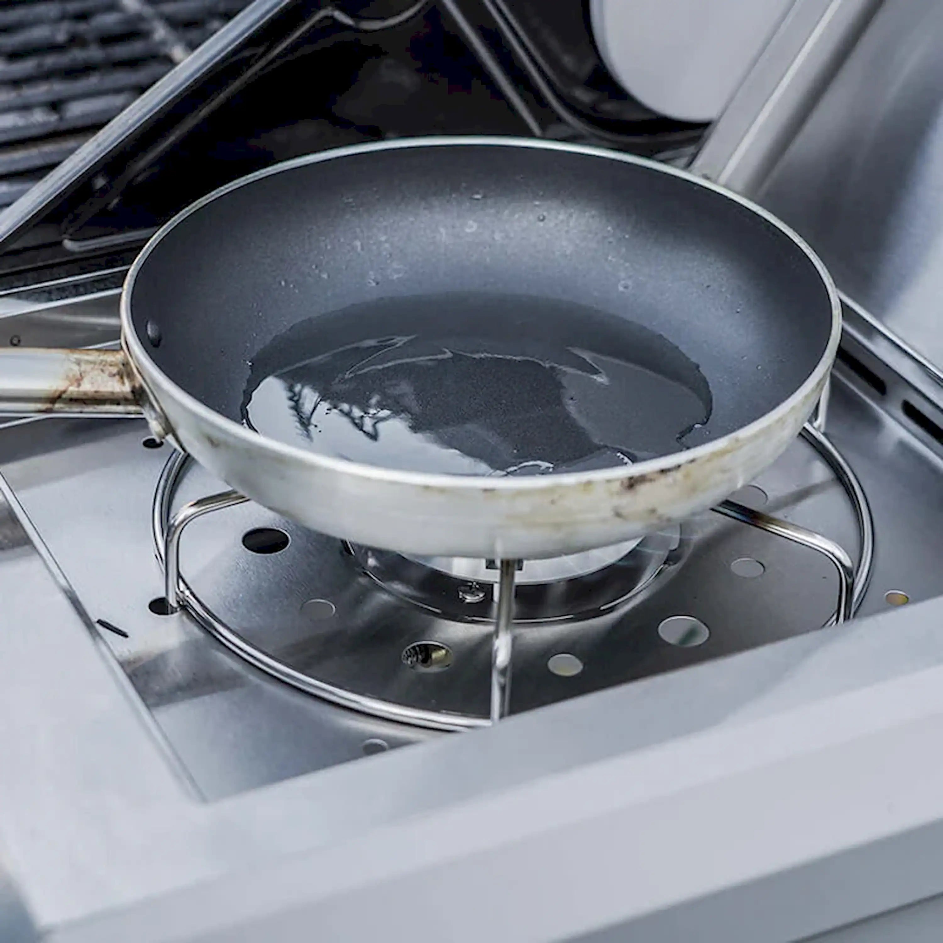 Circular burner bowl on stainless steel grill grate with flame opening