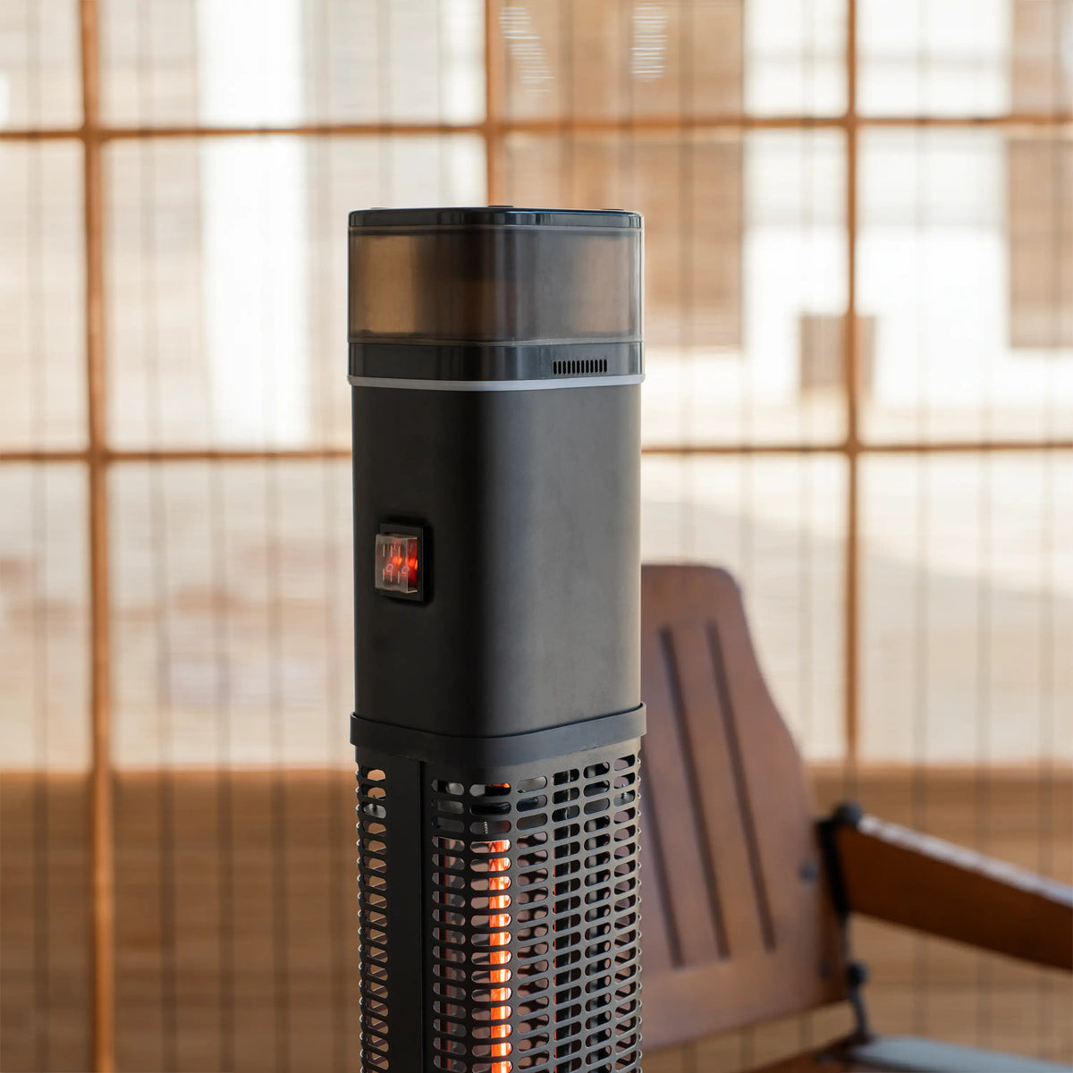 Black column heater with glowing halogen tube and control indicator on side