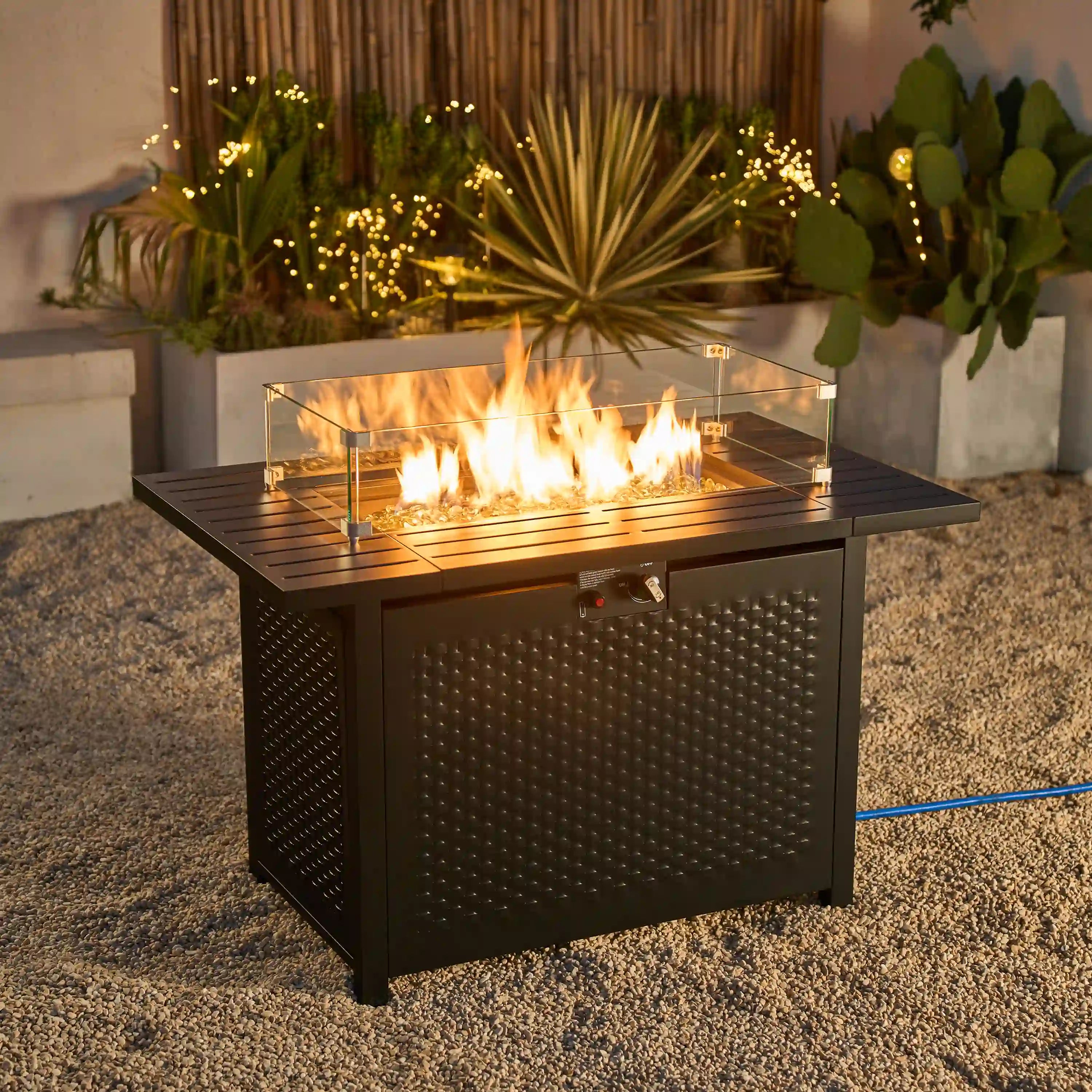 Outdoor propane fire pit table with visible flame through glass wind guard