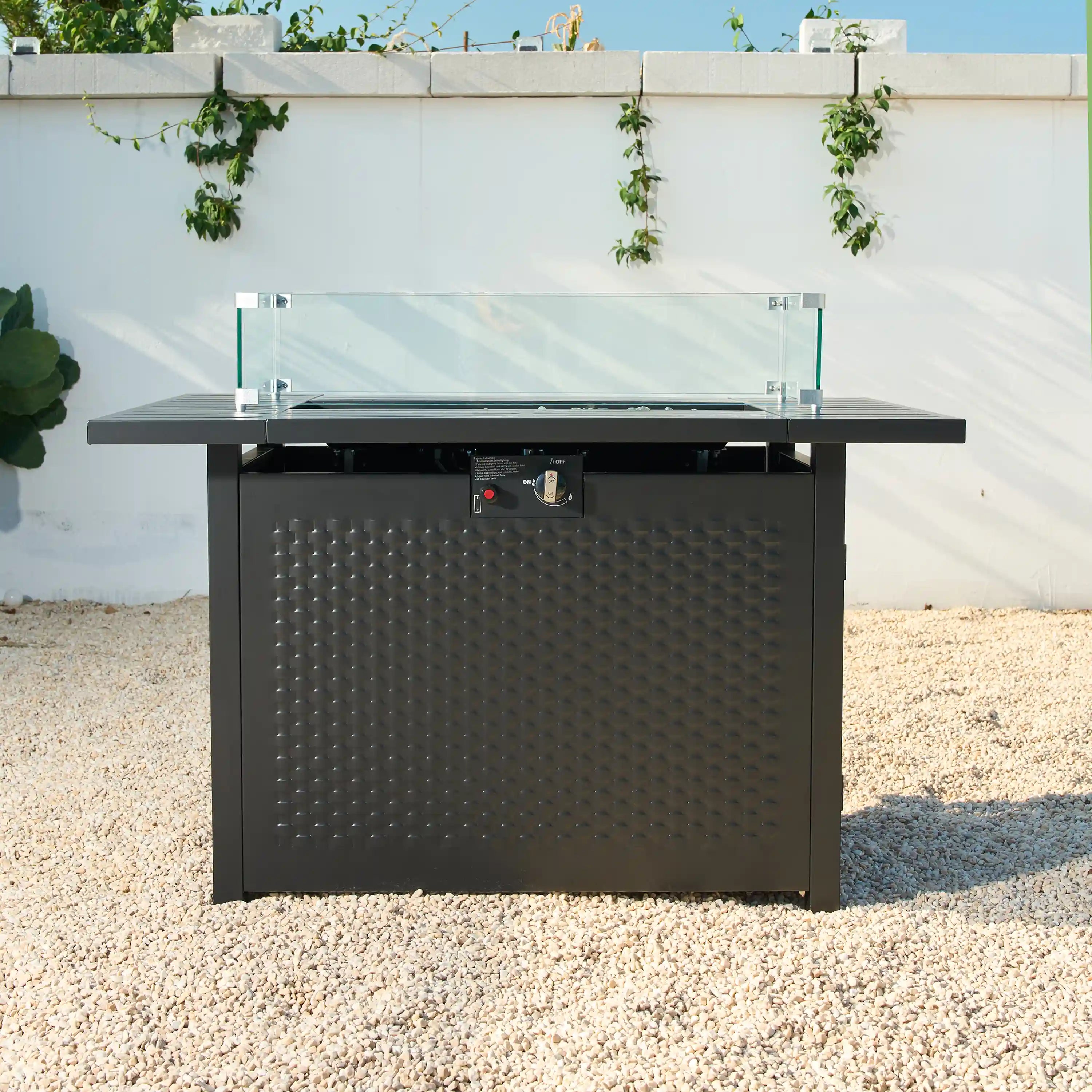 Front view of dark outdoor fire pit table with control knobs and glass guard