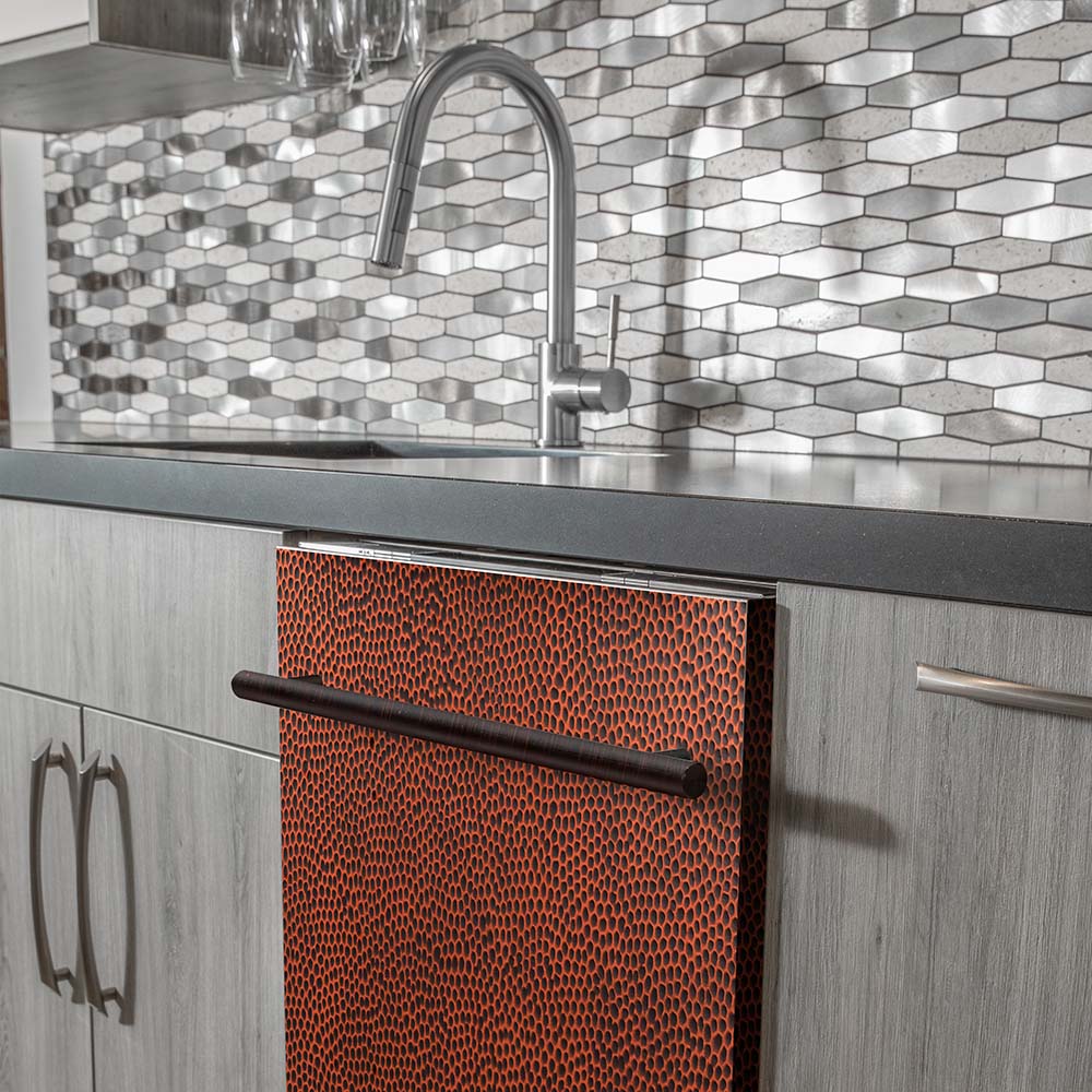 Installed dishwasher with hand-hammered copper door and stainless handle in cabinetry.