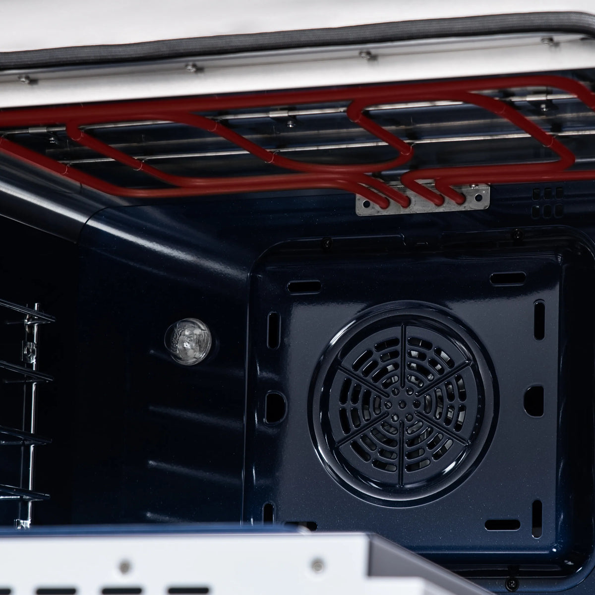 Rear oven cavity view with red gas lines and black circular ventilation cover