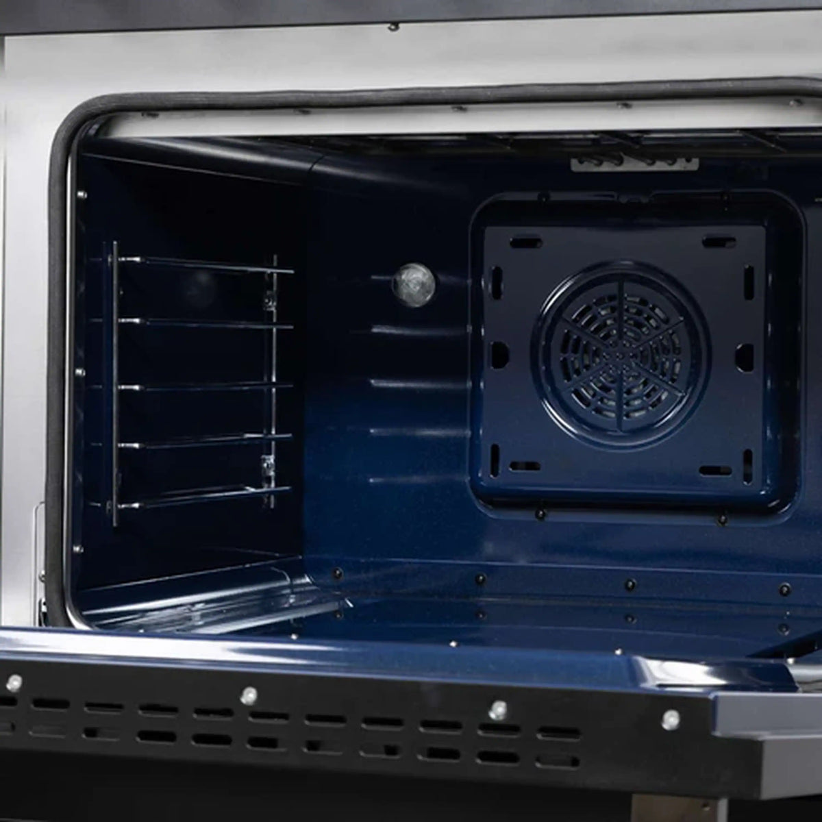 Close-up of dual fuel range oven floor with vent panel and black interior surfaces