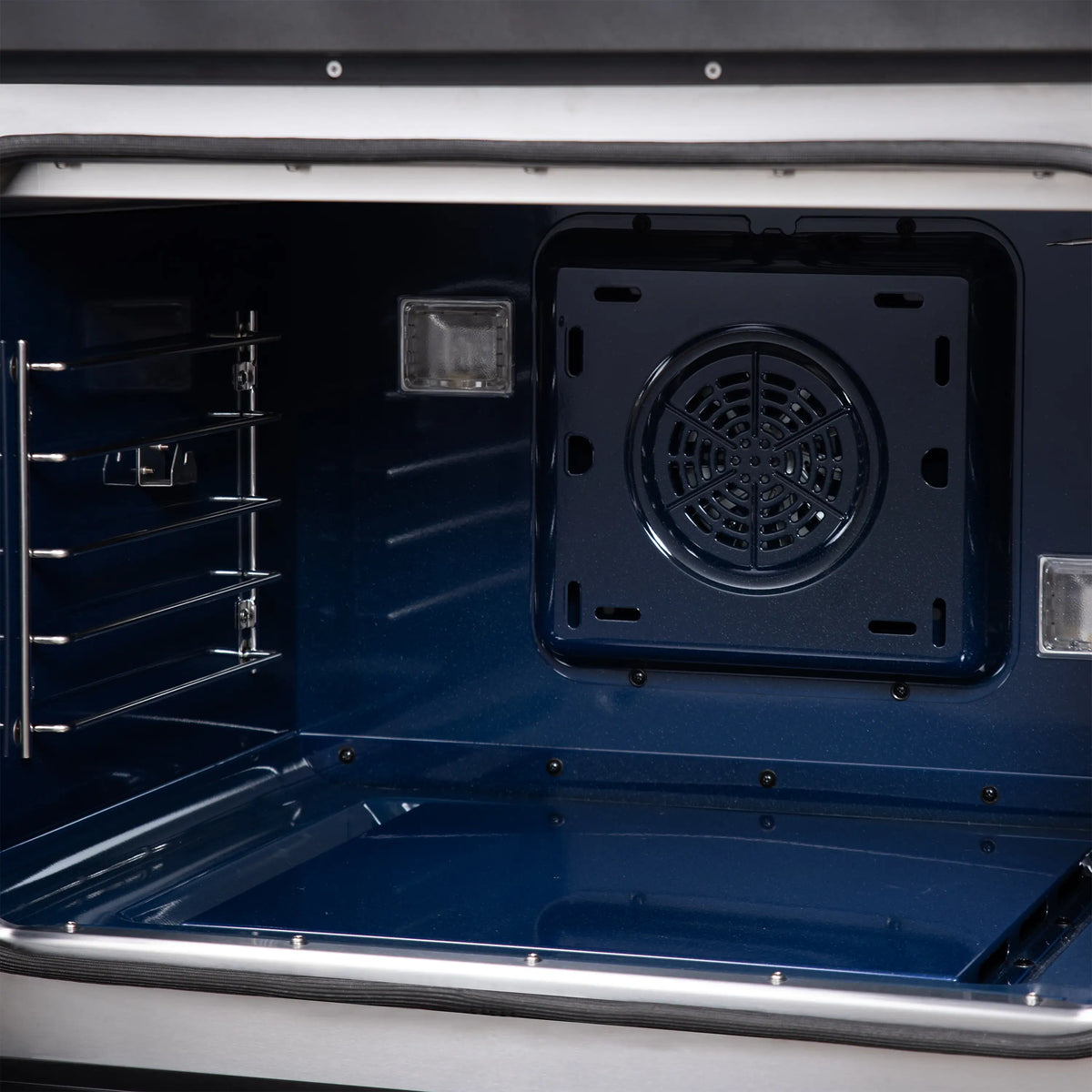 Dual fuel range oven interior with blue back panel and circular ventilation plate