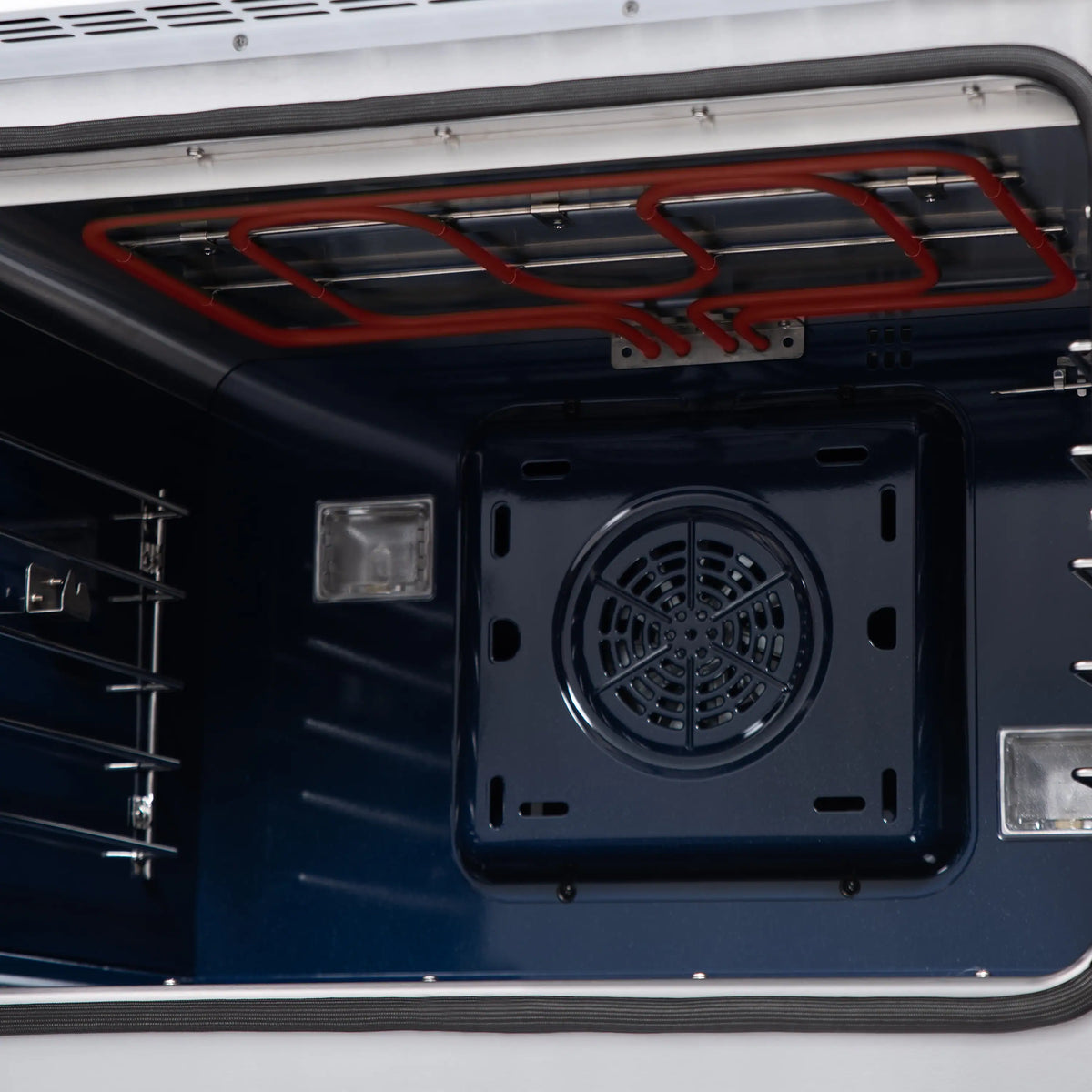 Dual fuel oven interior with exposed red heating element wiring and round fan vent.