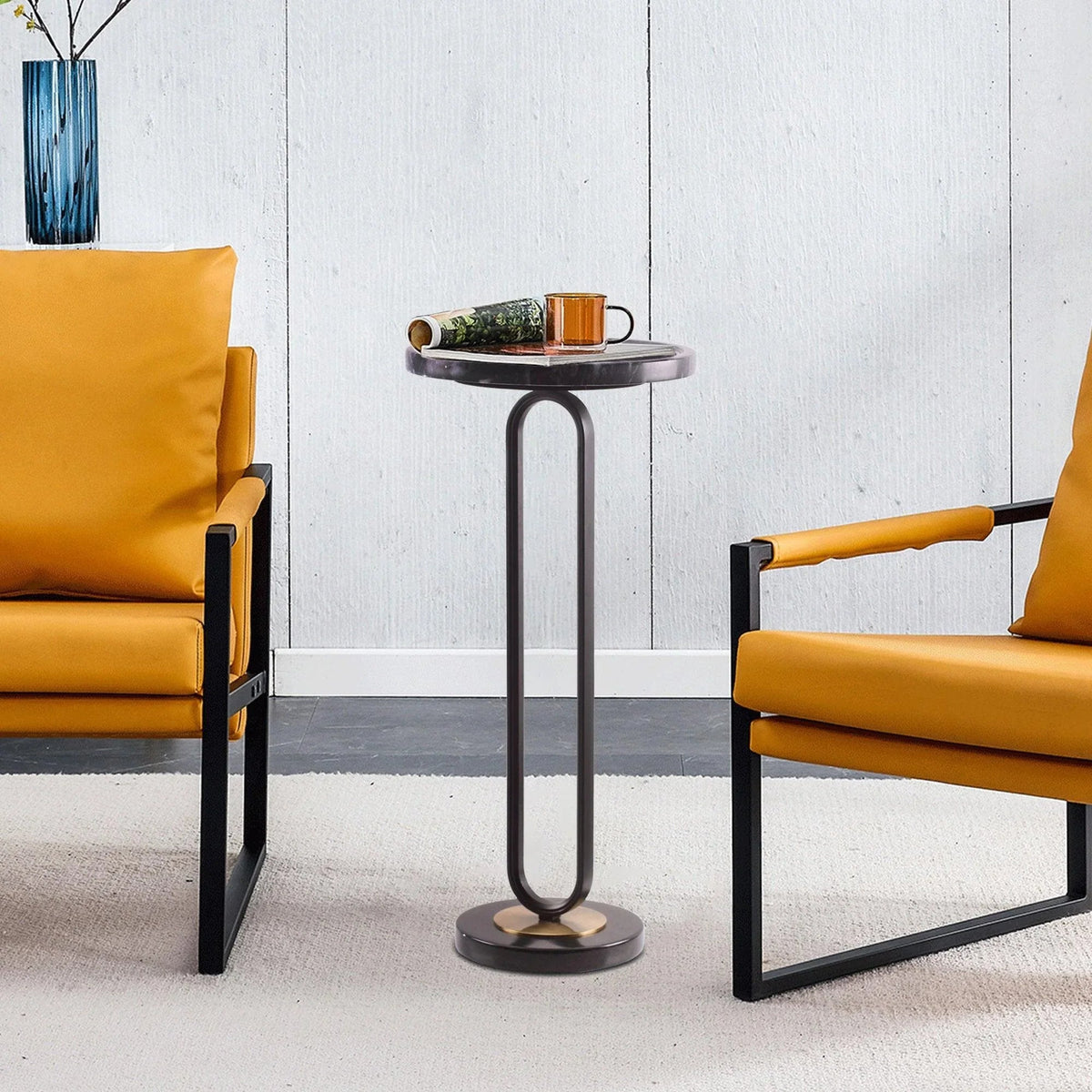 Black round side table with metal legs and dark stone-look top in living room setting