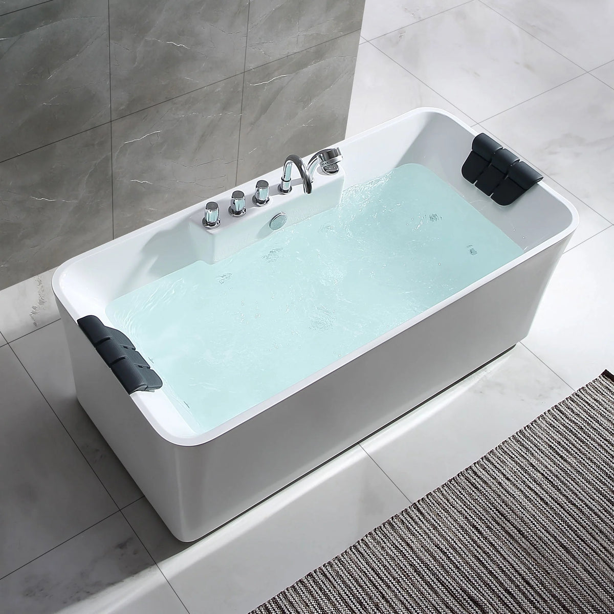 White freestanding acrylic whirlpool bathtub with black headrest and chrome jets over aqua water.