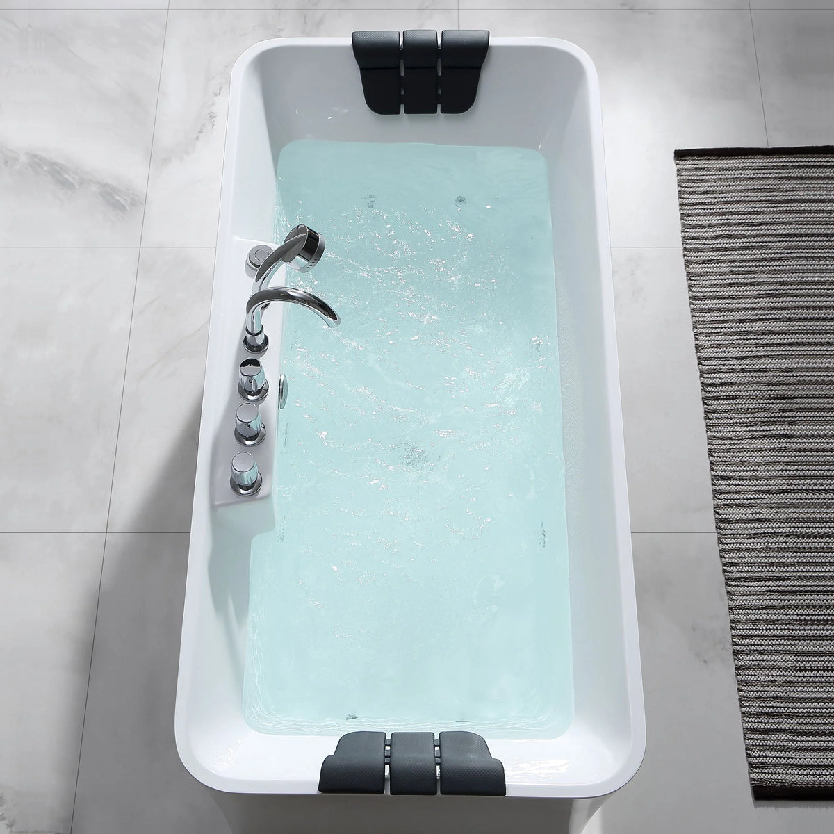 Rectangular white acrylic whirlpool bathtub with black headrests and aqua water, top view.