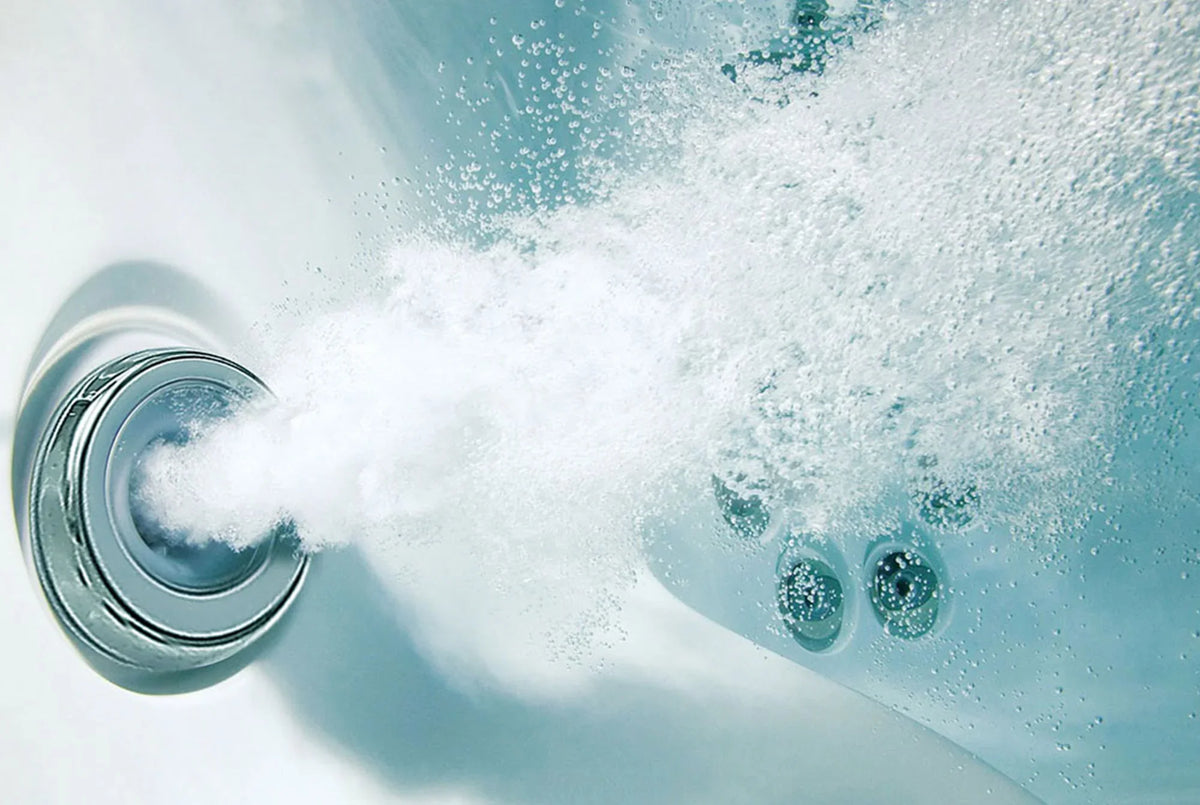 Hot tub jet close-up with bubbling water and chrome nozzle