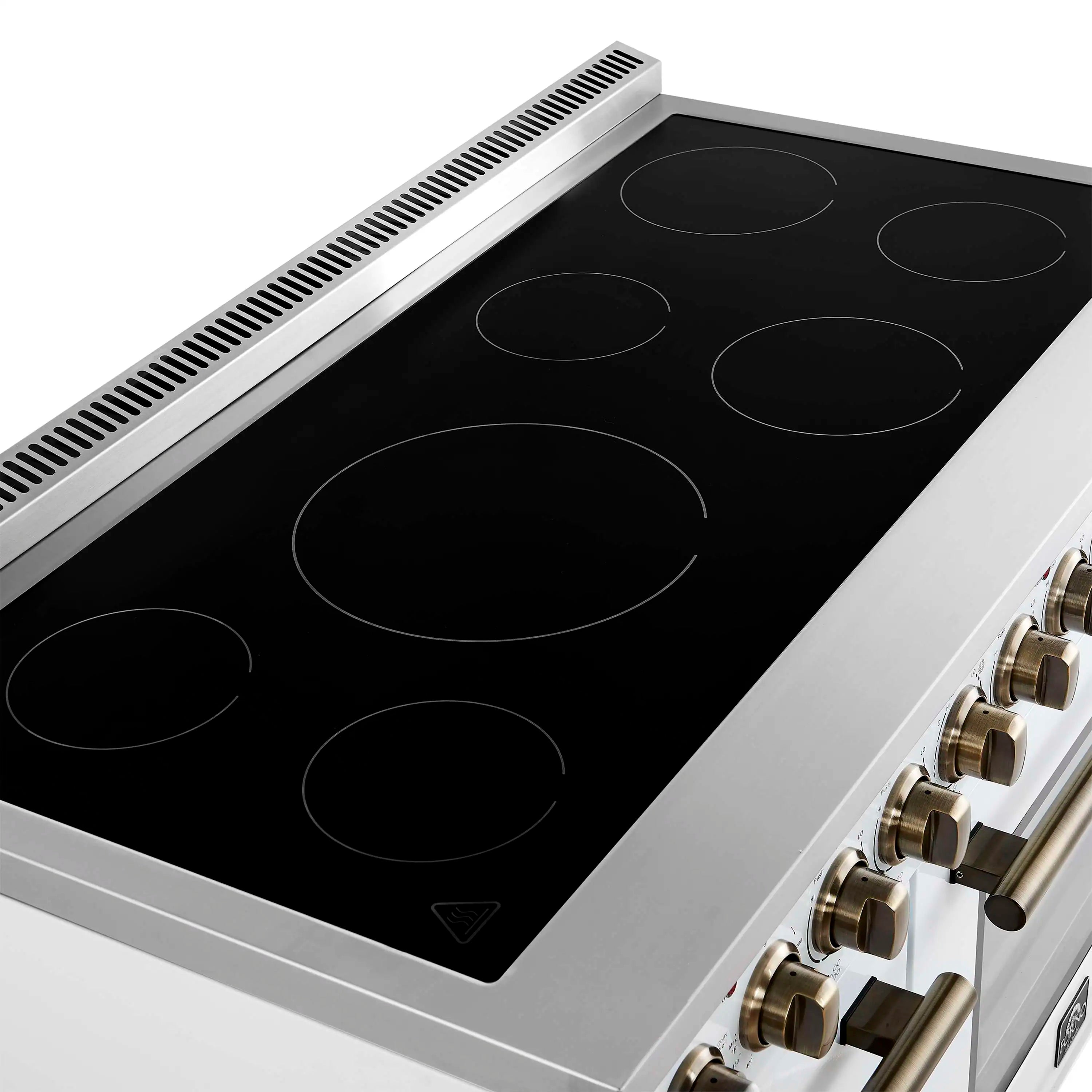 White electric range cooktop on black glass with brass control knobs