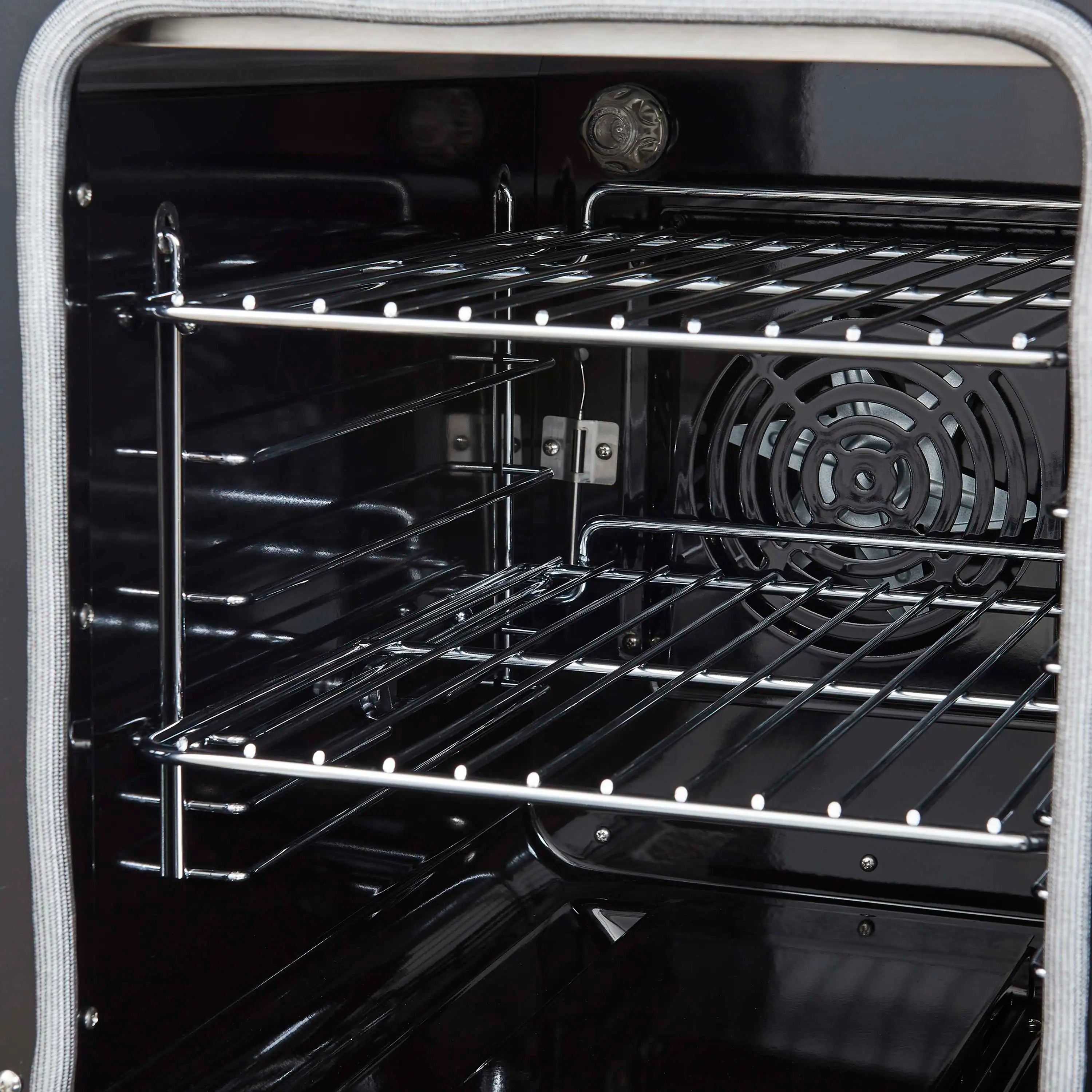 Stainless steel electric range oven interior with racks and circular fan assembly