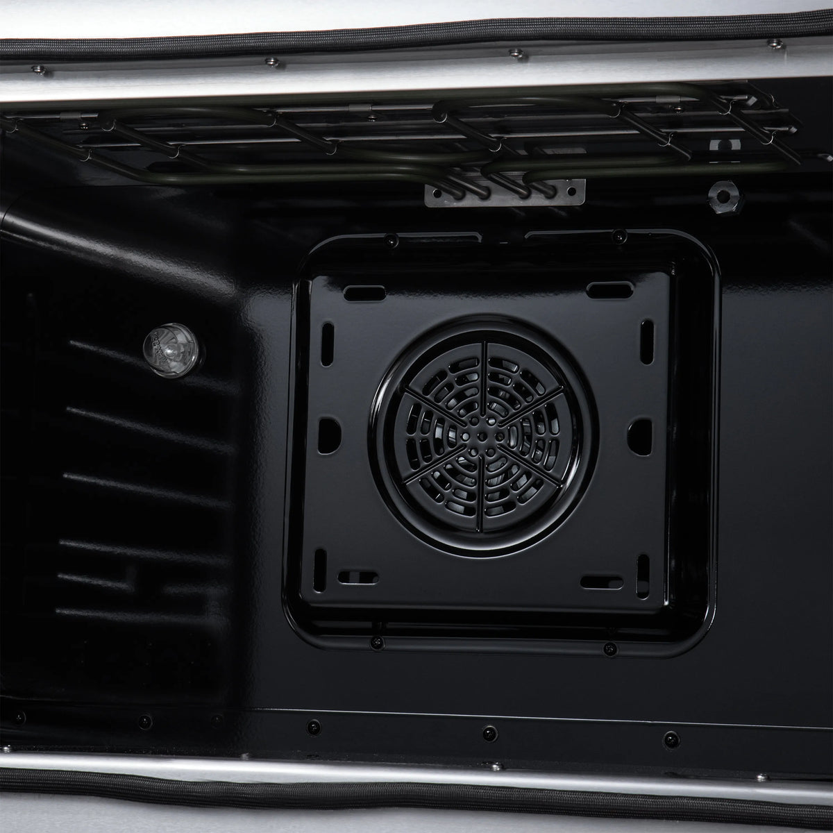 Electric oven cavity showing round convection fan and vent grille