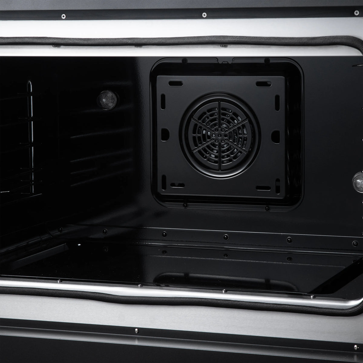 Electric oven interior panel with round convection fan, black metal walls and rails