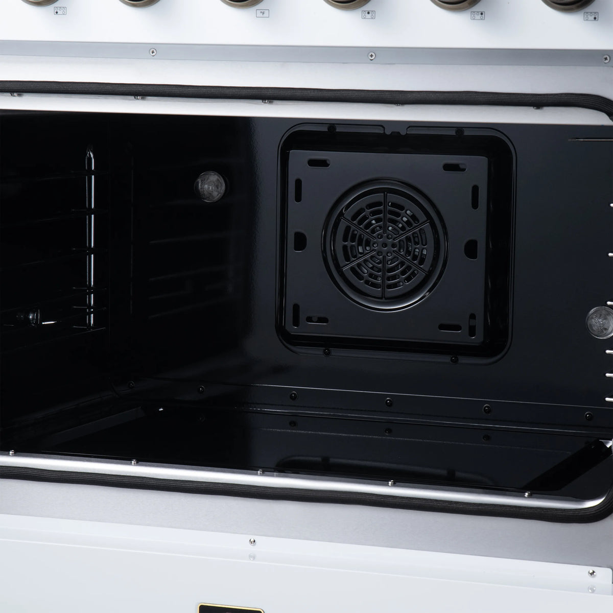 Black electric oven cavity with circular fan vent opening and side rack guides
