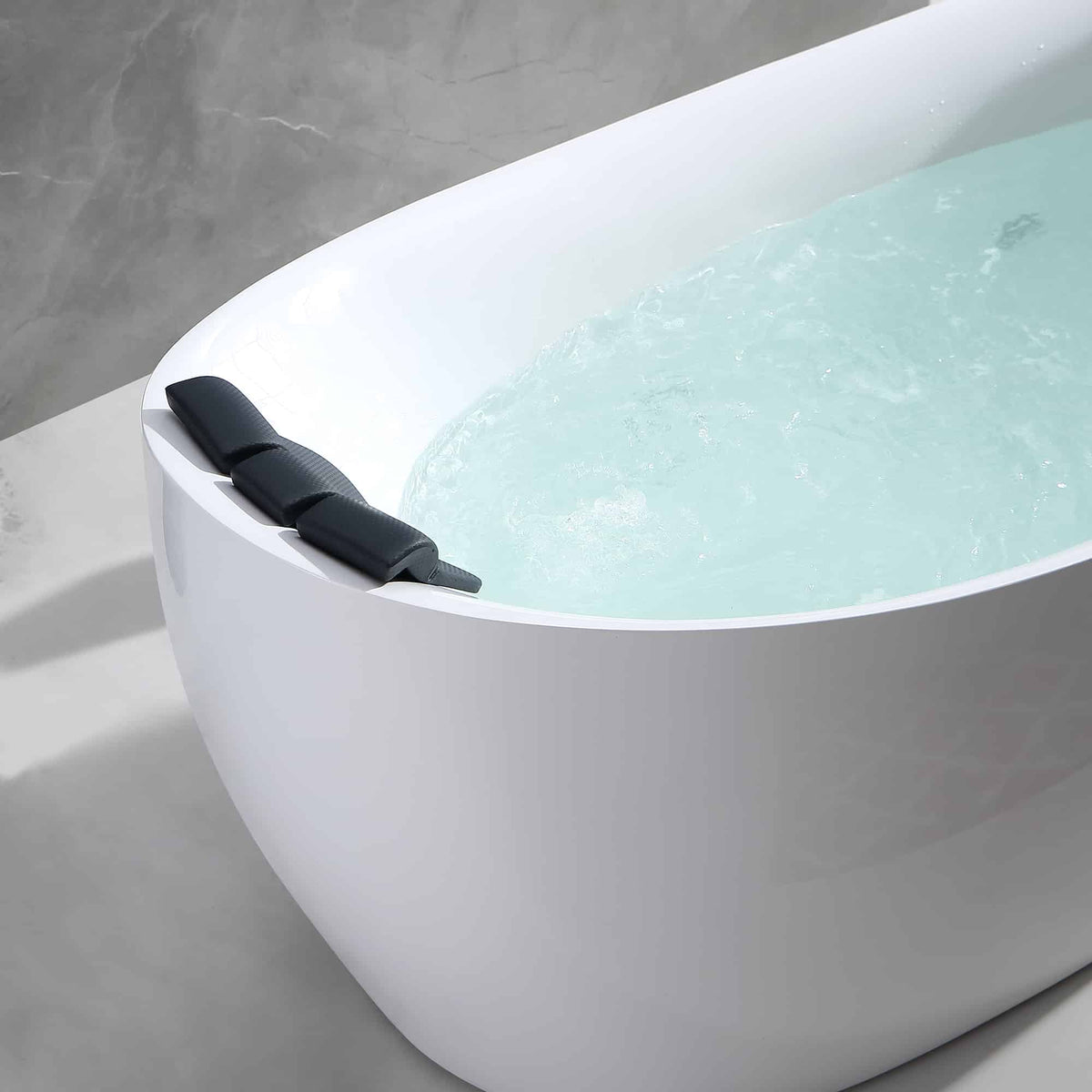 Close-up of white acrylic whirlpool bathtub with black headrest and water jets