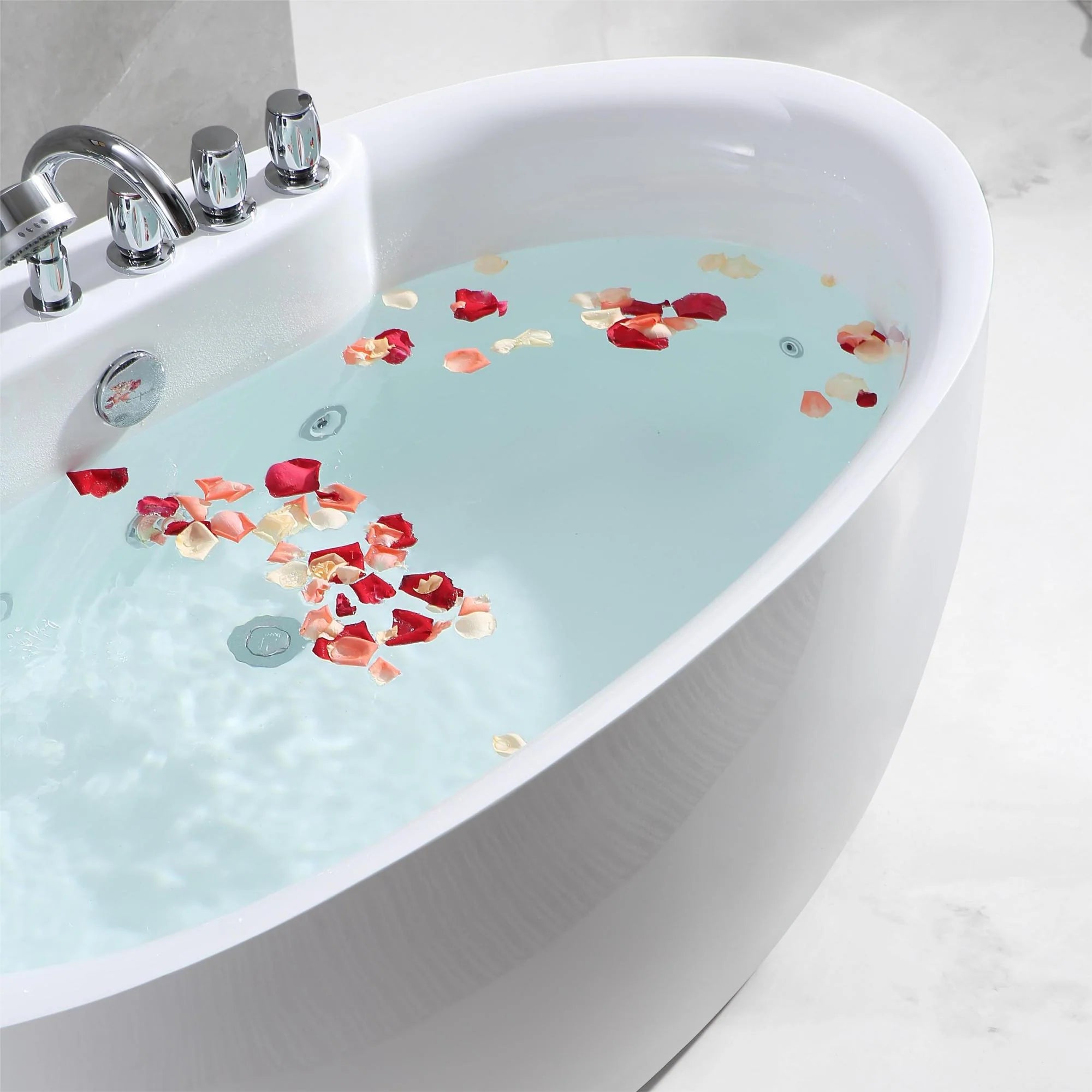 Close-up of white whirlpool bathtub with blue water and rose petals