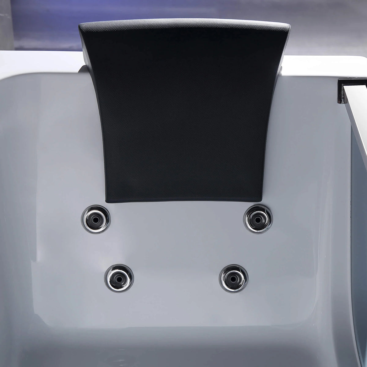 White whirlpool bathtub with black headrest and circular jet nozzles