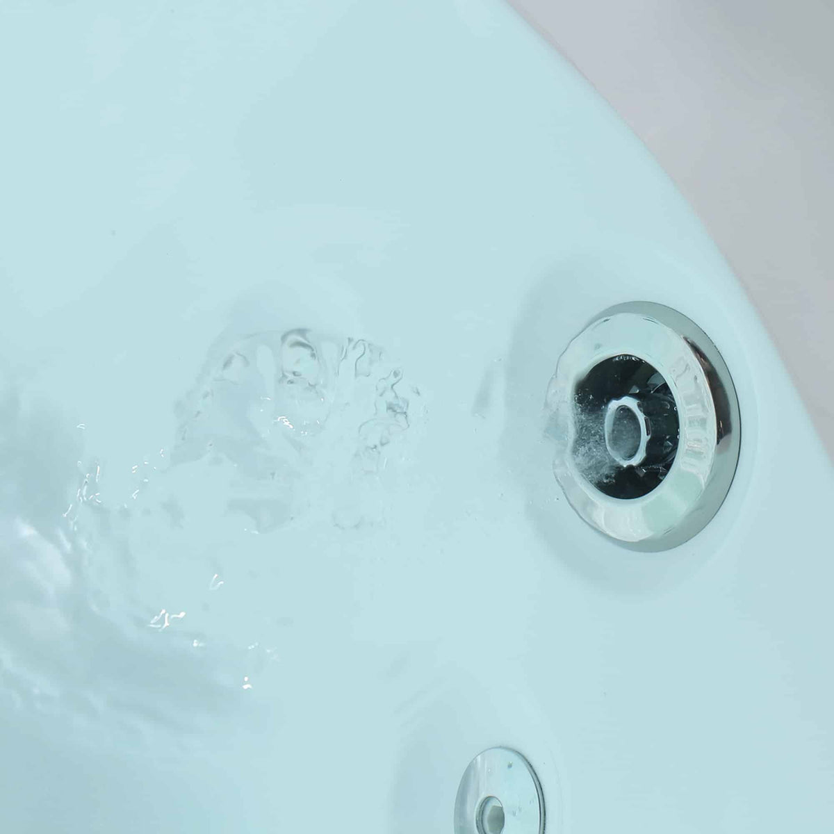 Close-up of round whirlpool jet on the inside wall of a white bathtub