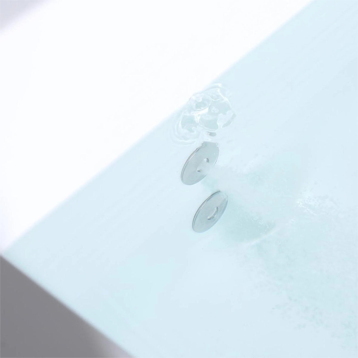 Close-up of whirlpool jet openings on the sloped floor of a white bathtub