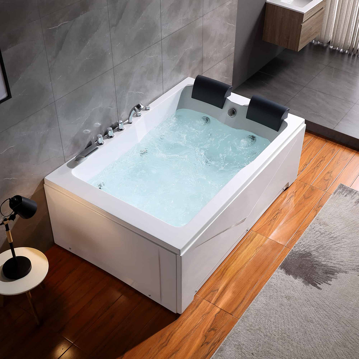 White whirlpool bathtub with blue-tinted water and two integrated black headrests