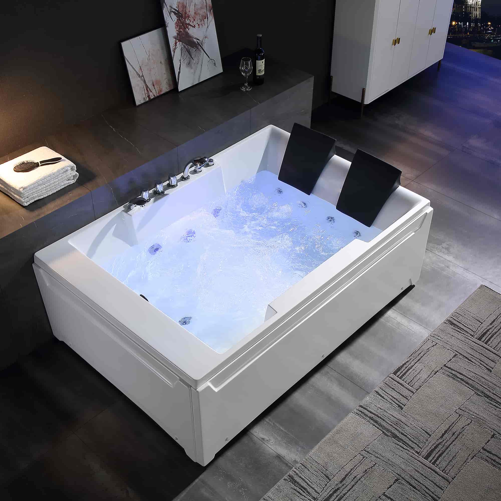 White rectangular whirlpool bathtub with chrome faucet and two black headrests