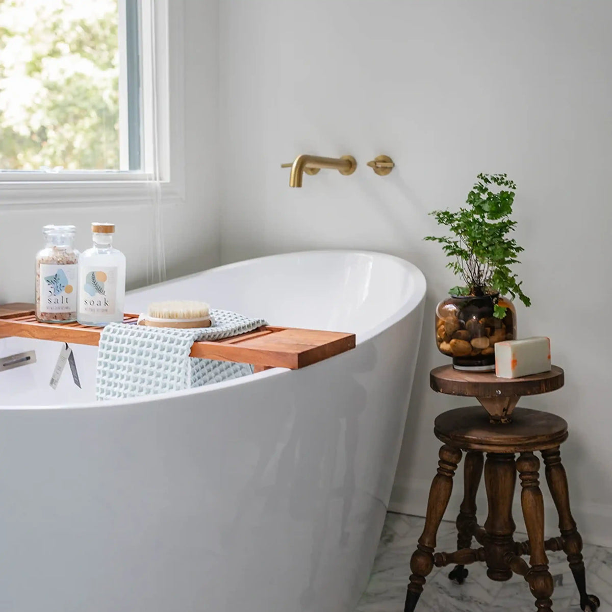 White freestanding soaking tub with gold faucet and chrome showerhead