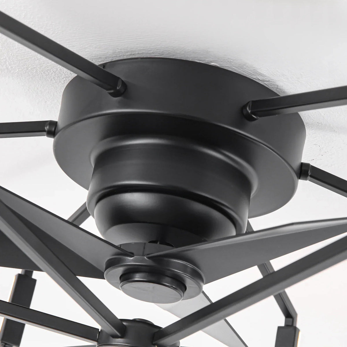 Close-up of black flush-mount ceiling fan motor housing and blade arms