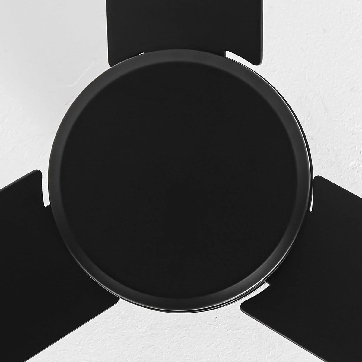 Black ceiling fan motor housing with blade arms radiating outward