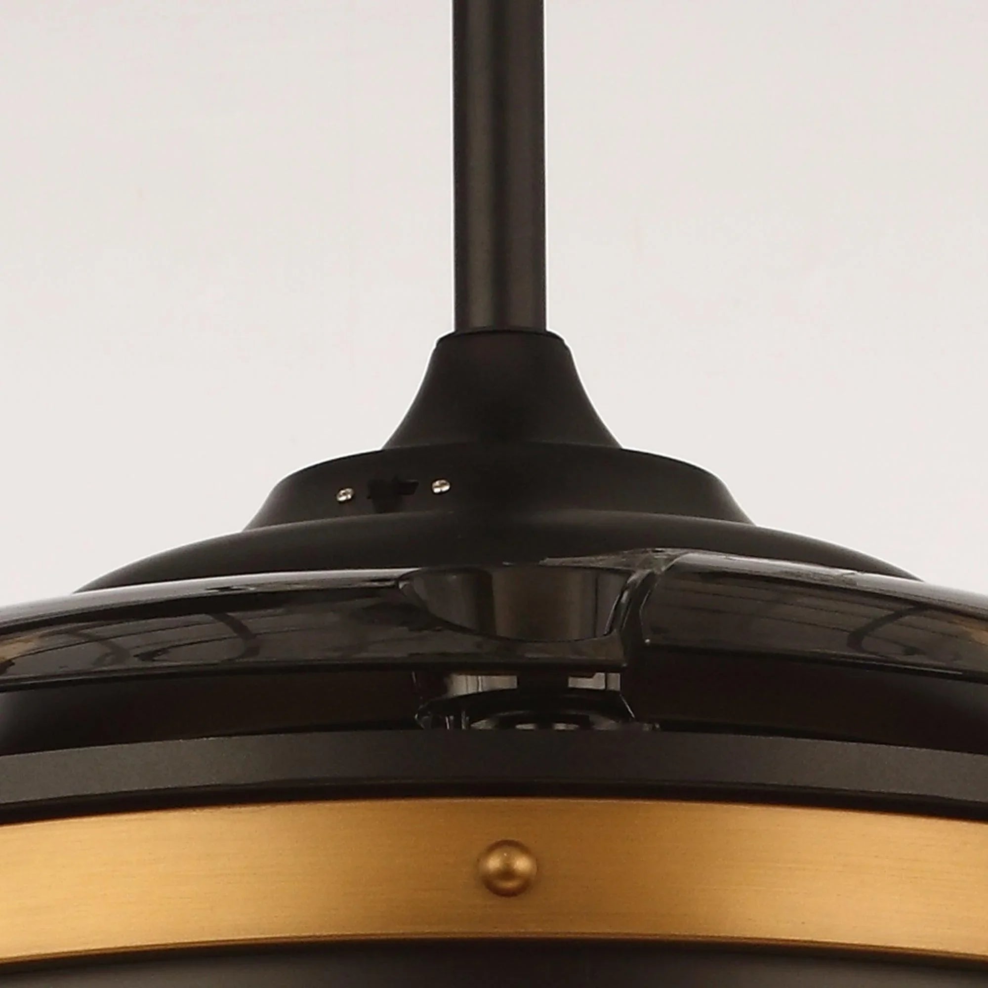 Close-up of black ceiling fan motor housing and bronze accent band.