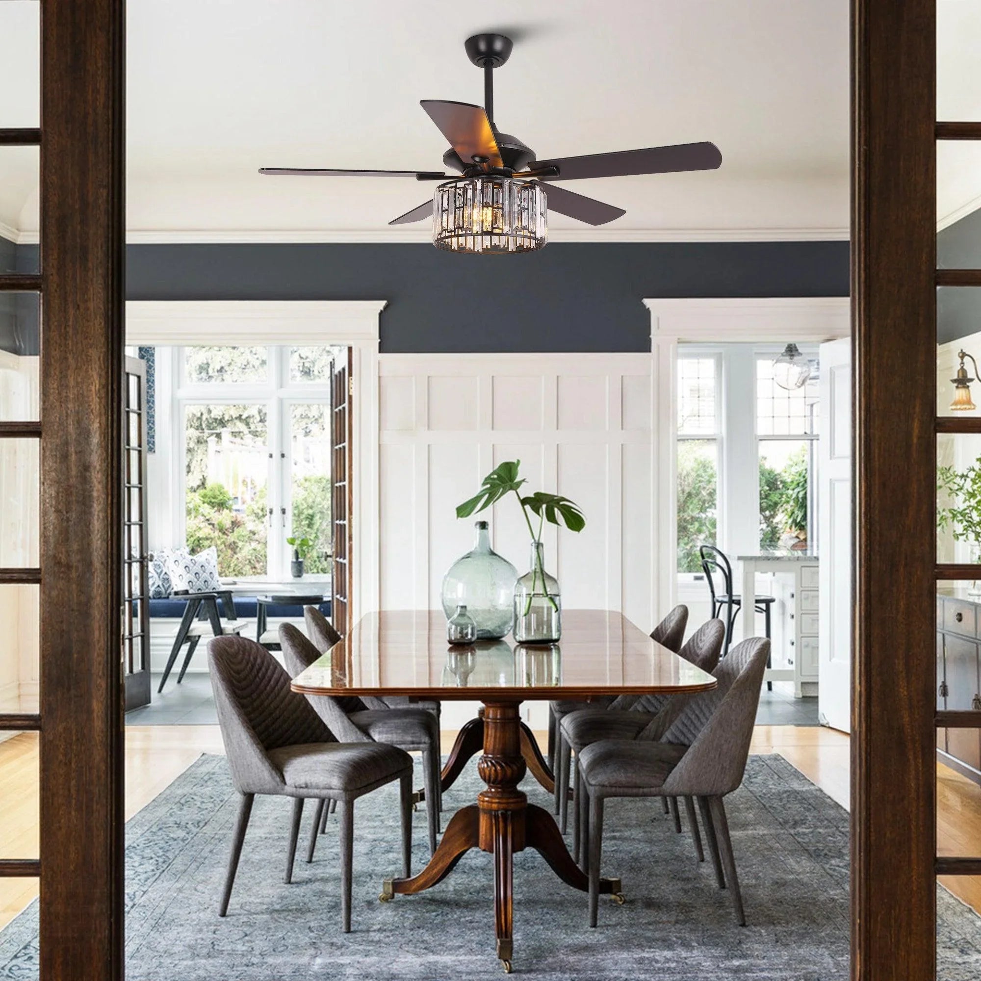 Ceiling fan with black motor cap, dark blades, and crystal drum light in a living room.