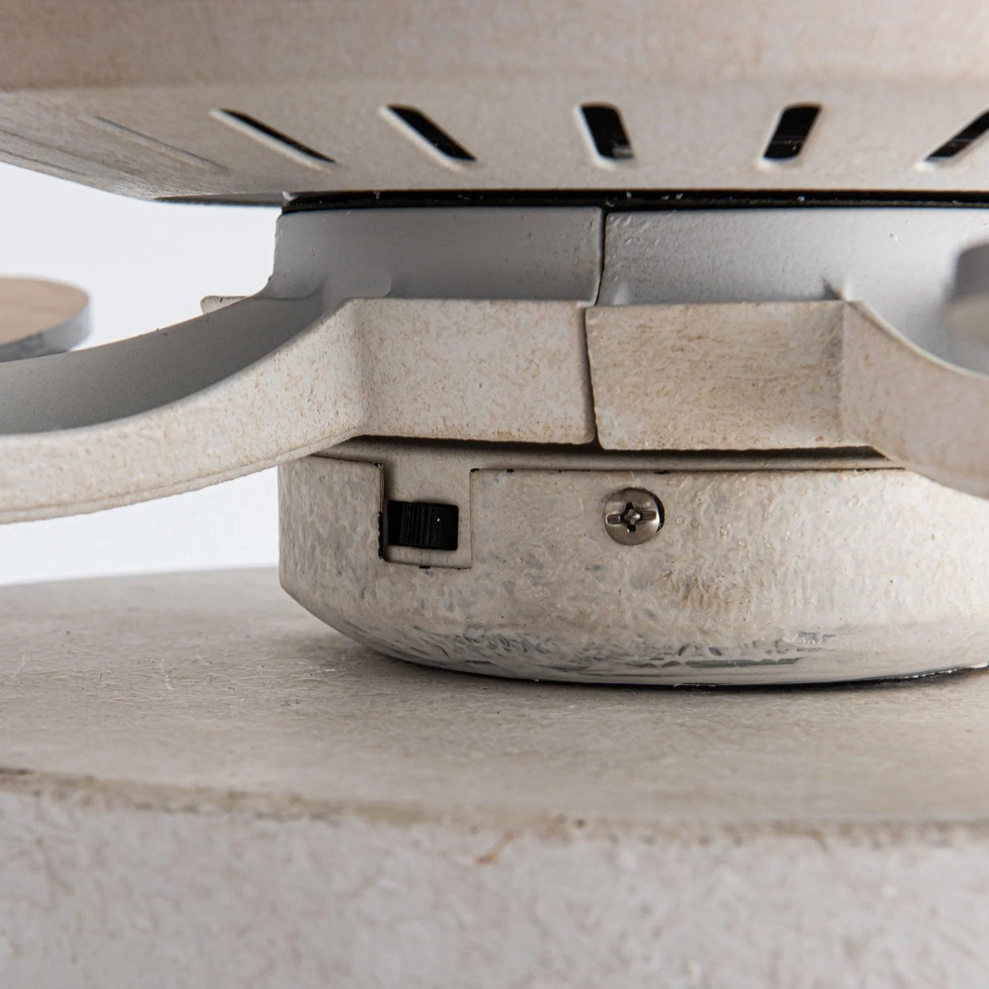 Ceiling fan motor housing underside detail with white finish and mounting screws