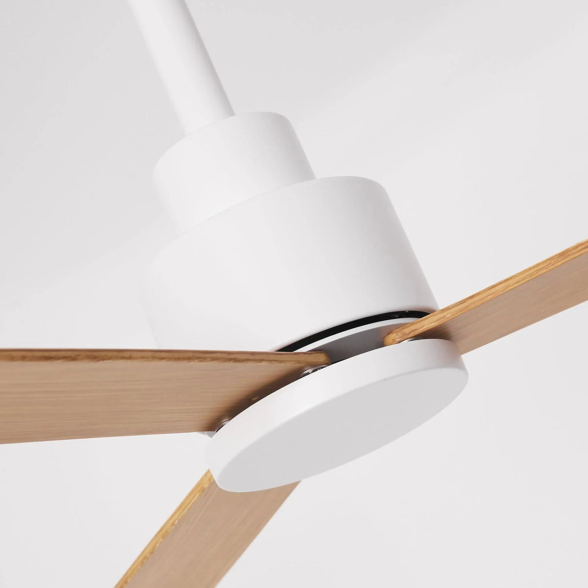 Modern ceiling fan with white motor housing and three light wood blades