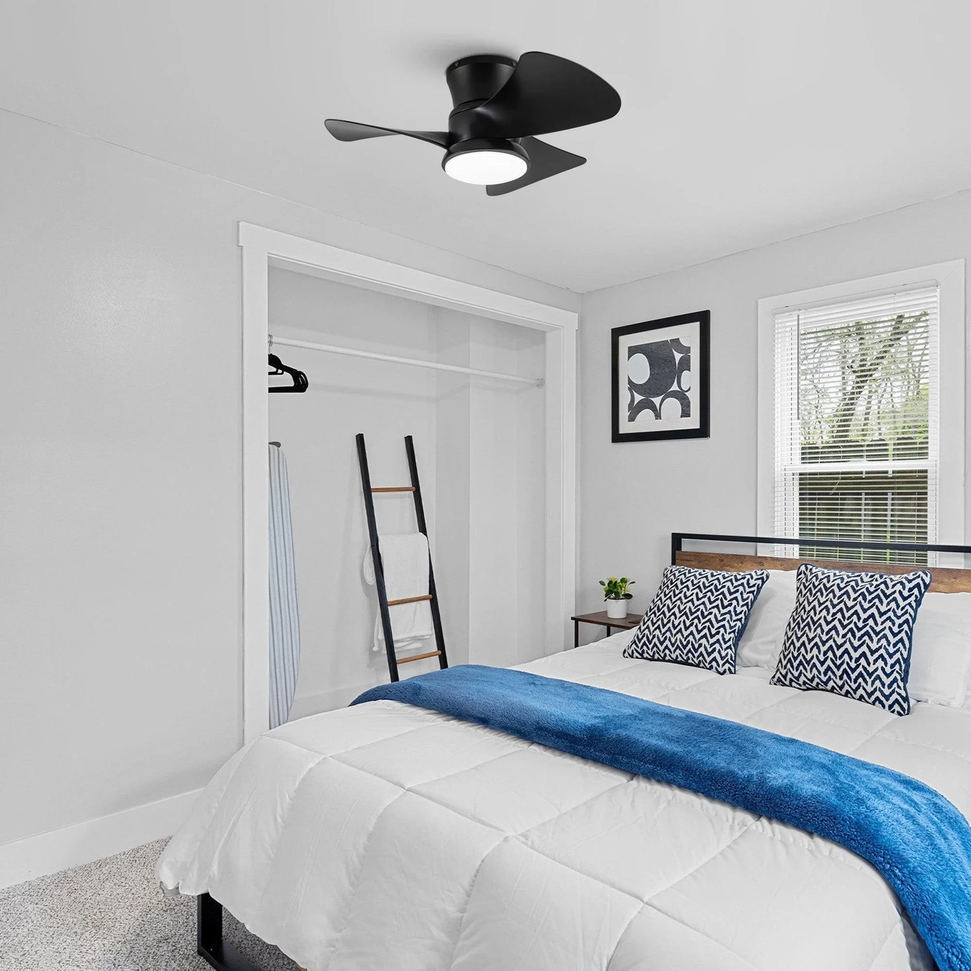 Black flush mount ceiling fan with integrated round LED light above a bed