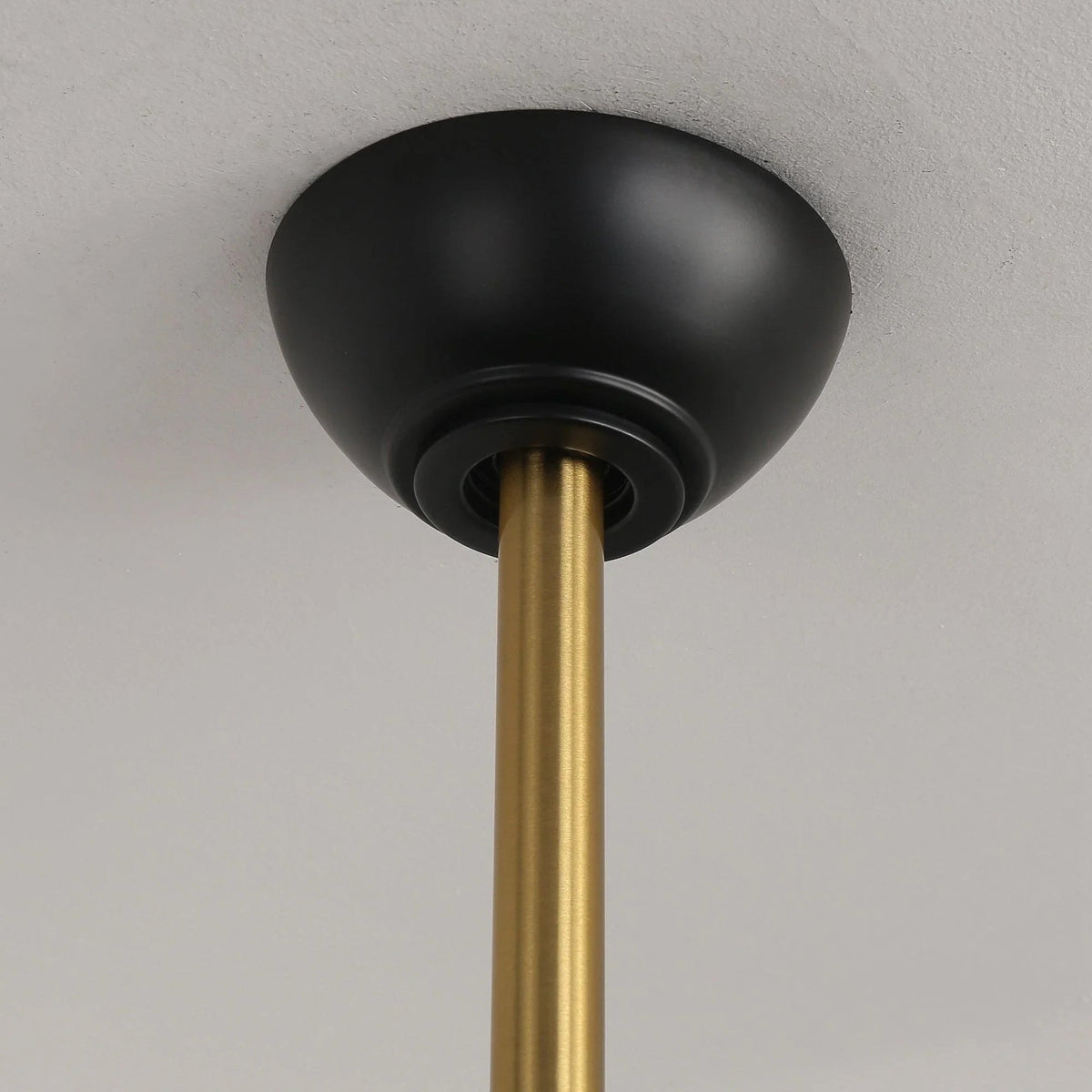 Ceiling fan motor housing with black canopy and gold downrod connector