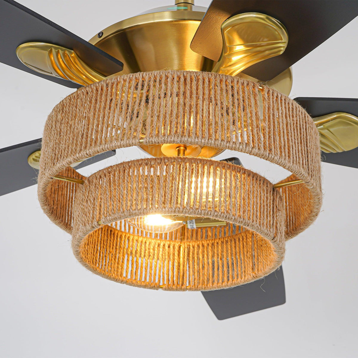 Golden ceiling fan with woven rope drum shade and lit bulbs, blades spread