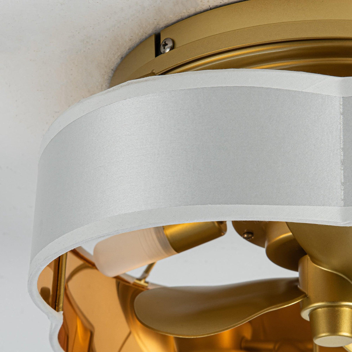 Golden flush mount ceiling fan light housing with white diffuser and partial blade view