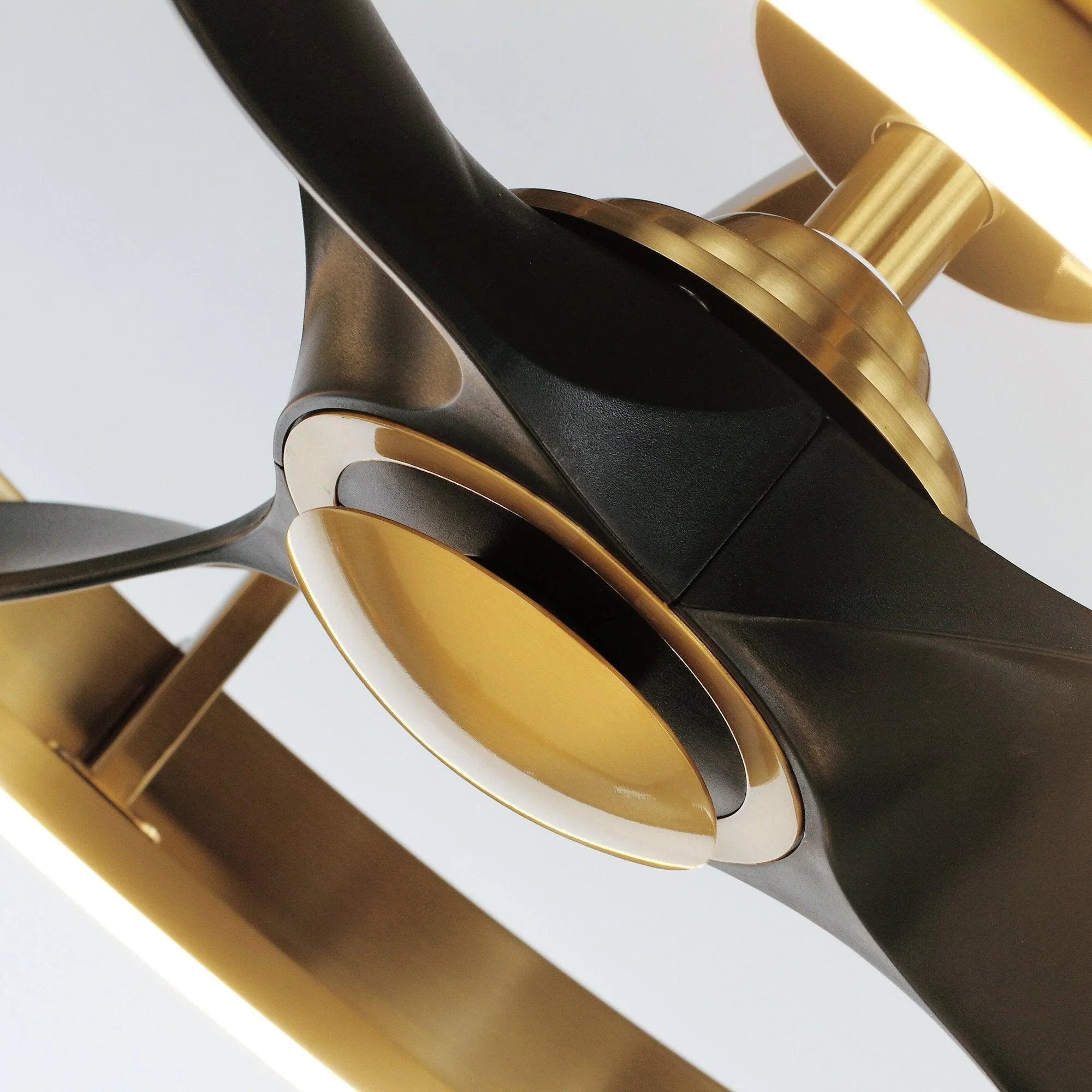 Golden ceiling fan blade hub with black blades and ring light detail