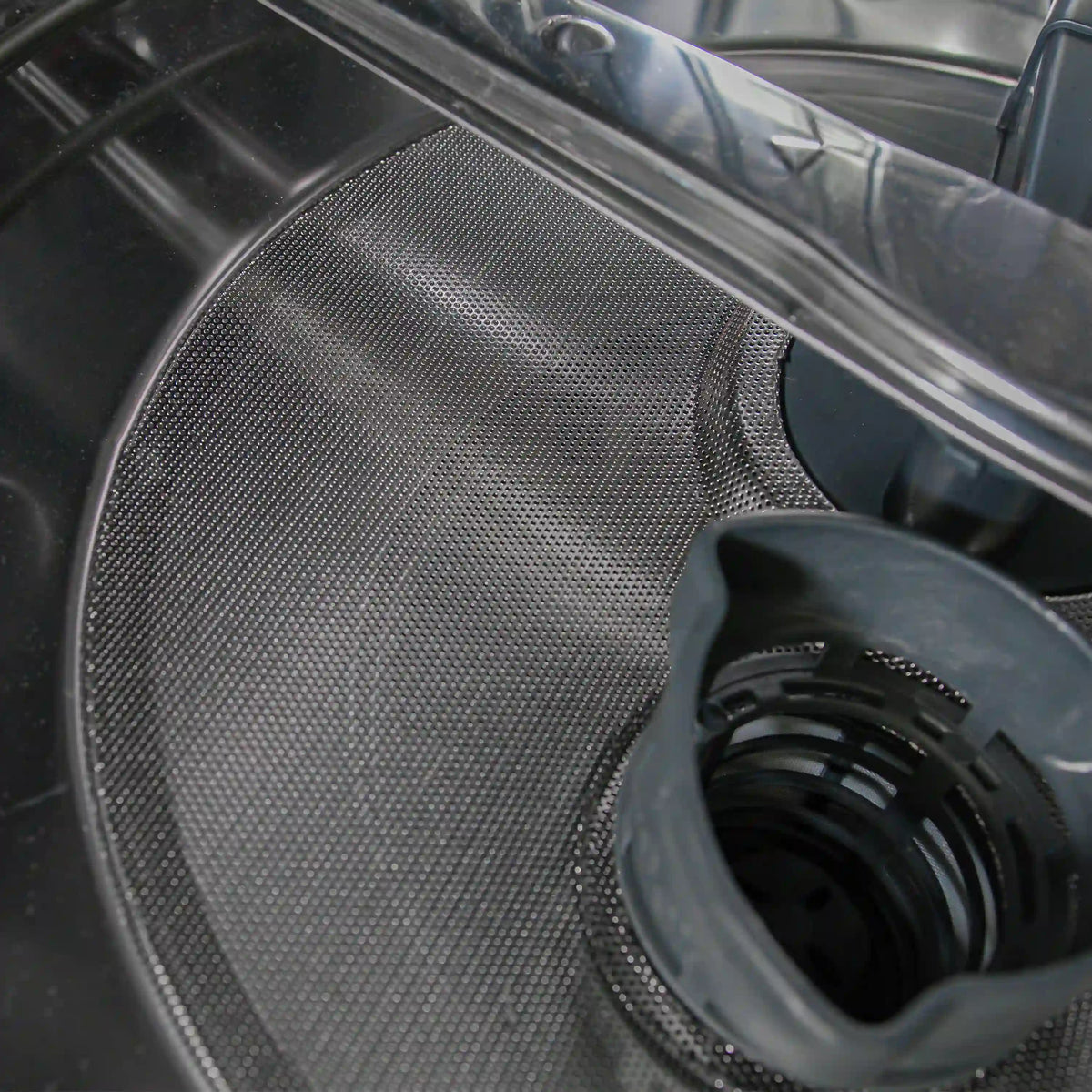 Dishwasher drain filter cover on stainless steel tub surface