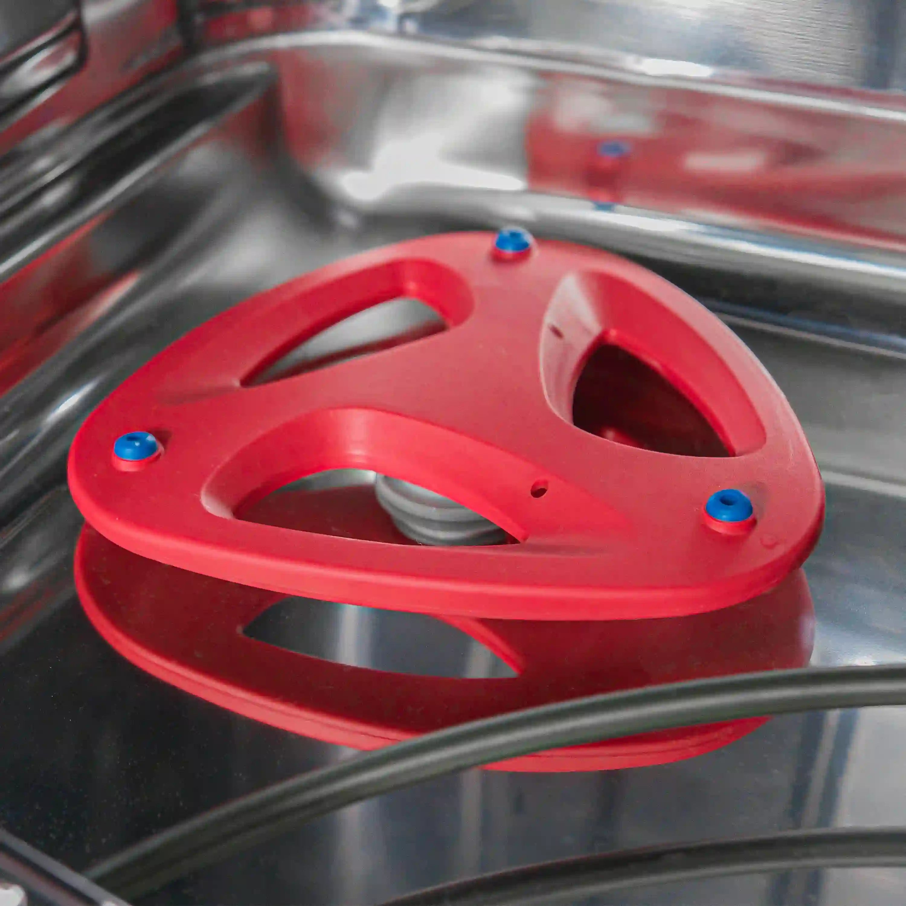 Red dishwasher utensil holder on stainless tub with spray arm behind