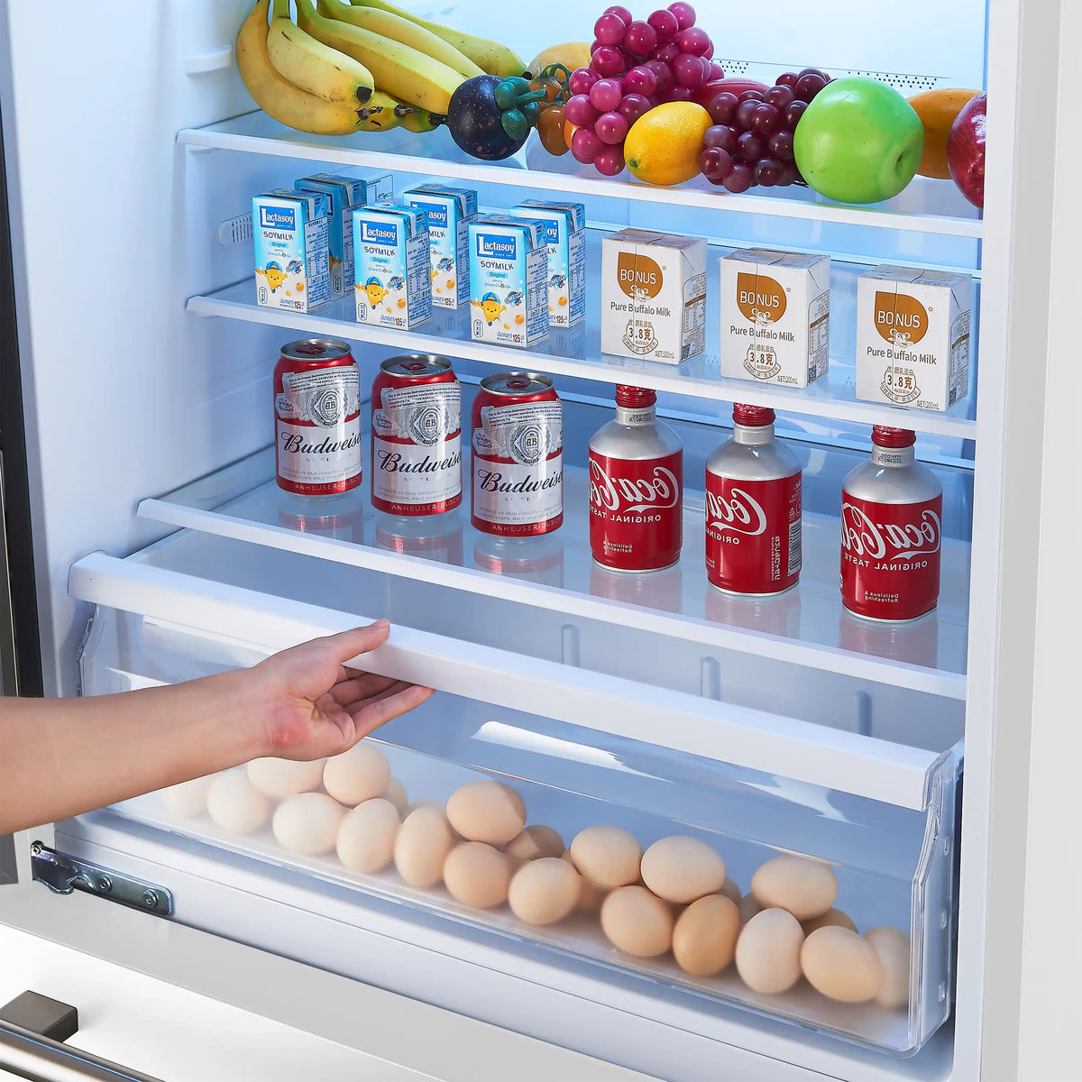 Refrigerator fresh-food drawer with eggs on shelf and hand pulling out tray