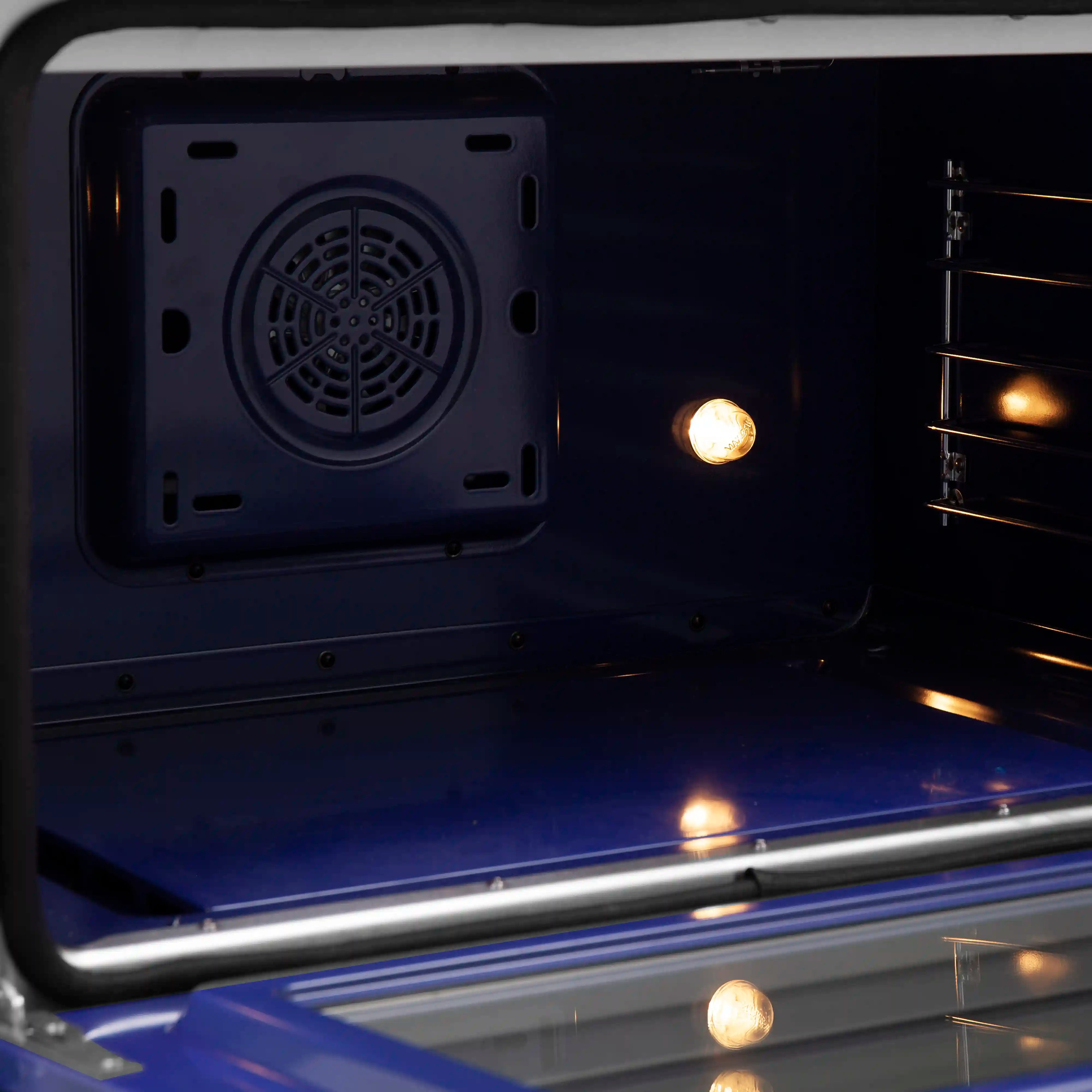 Electric range oven interior with vent fan cover and warm glowing heating elements