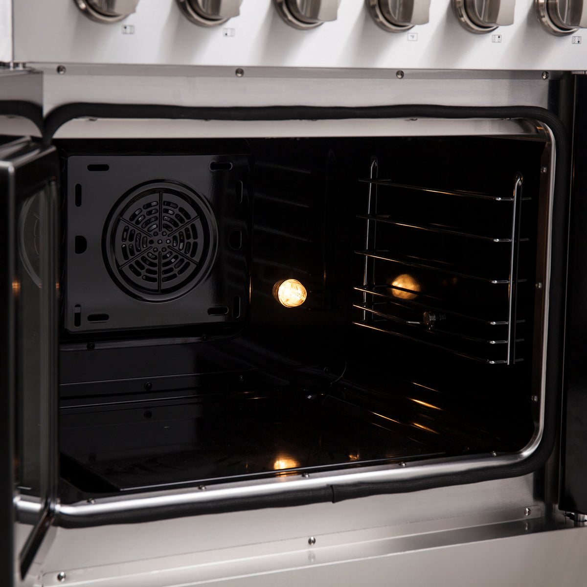 Open oven cavity with dark interior, side racks, and circular fan vent