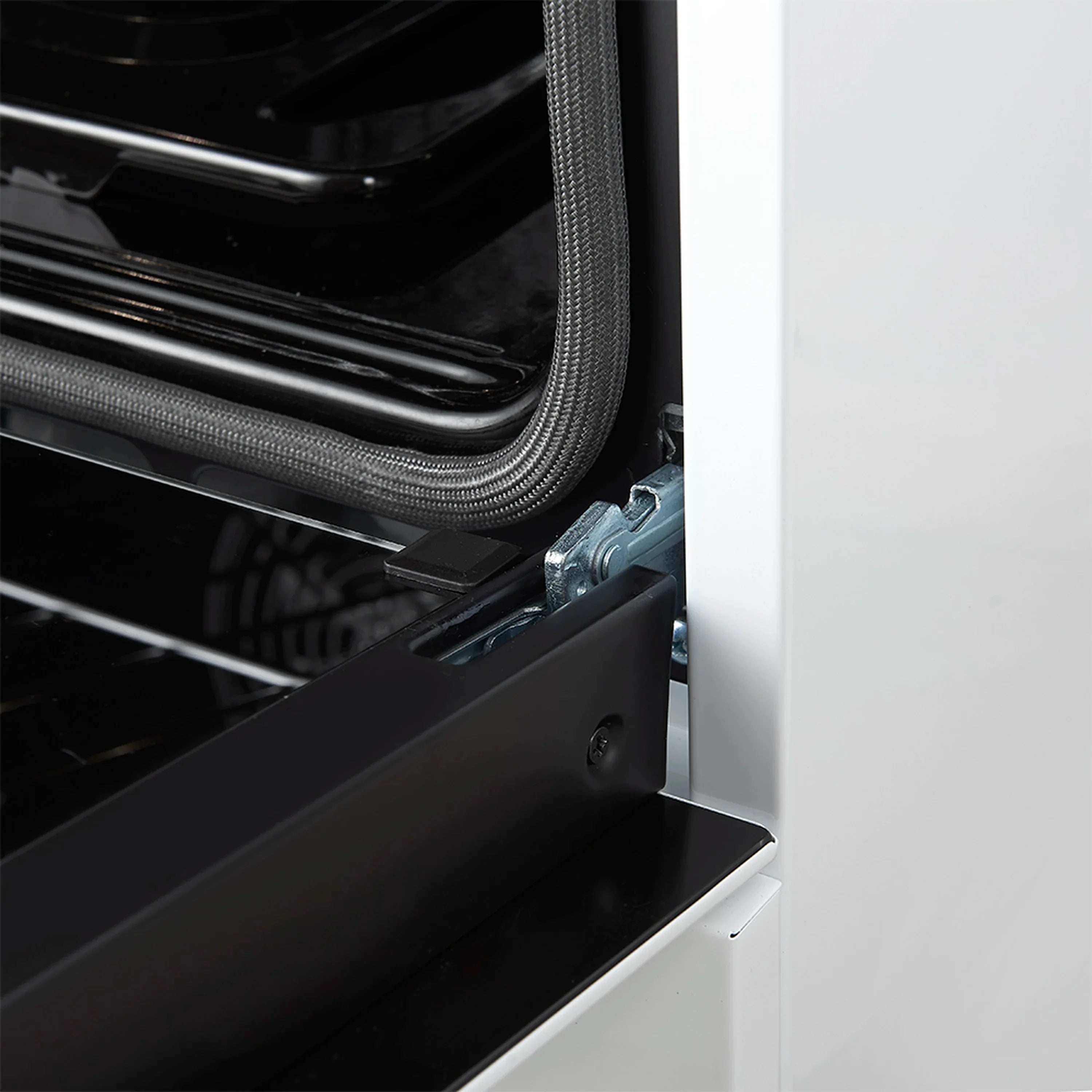 Oven door hinge and black tray support inside a white range