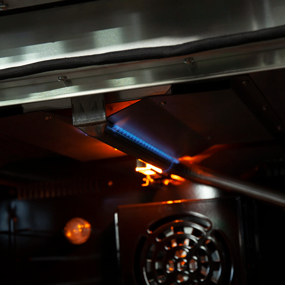 Gas oven burner area with visible blue flame