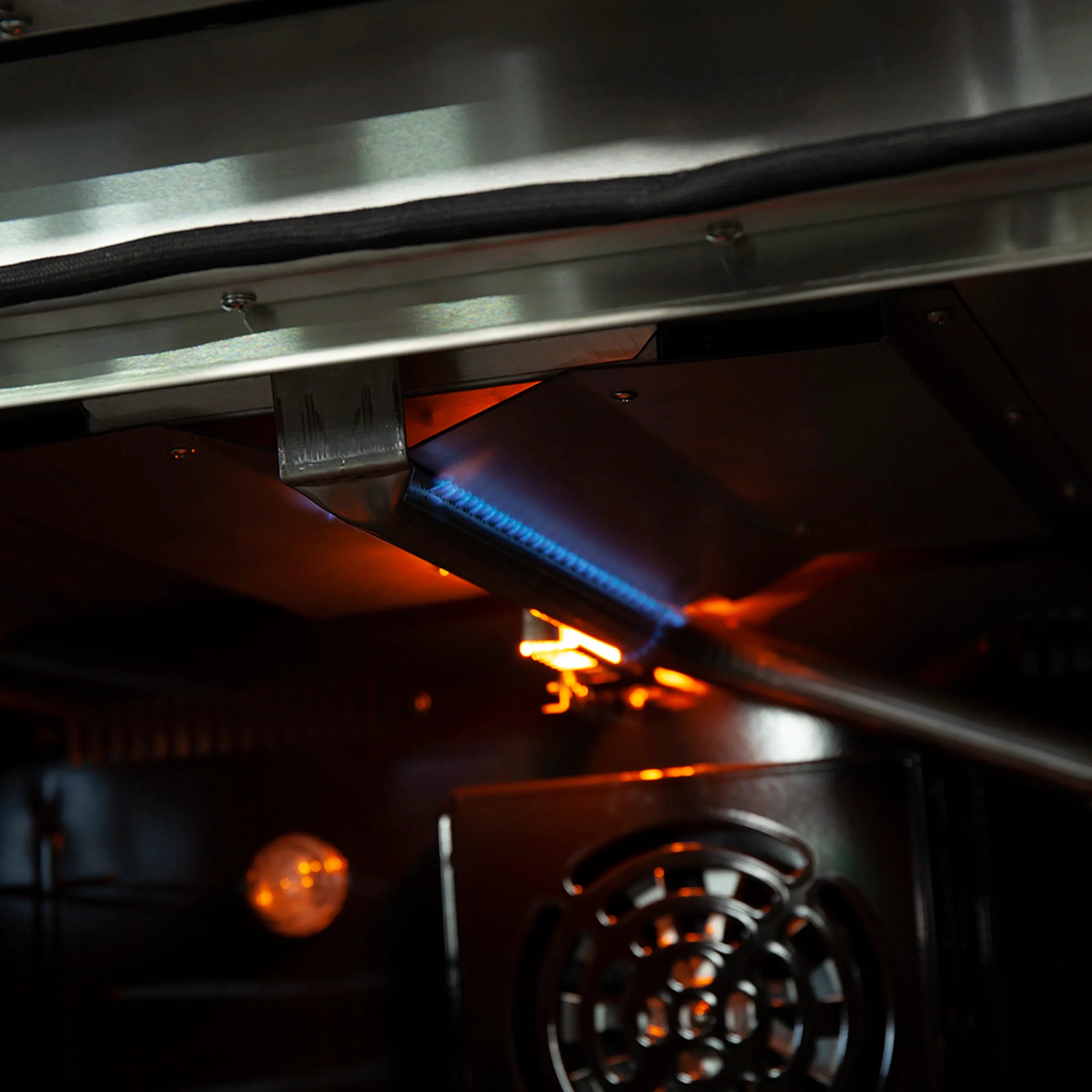 Gas oven cavity with visible blue and orange flames
