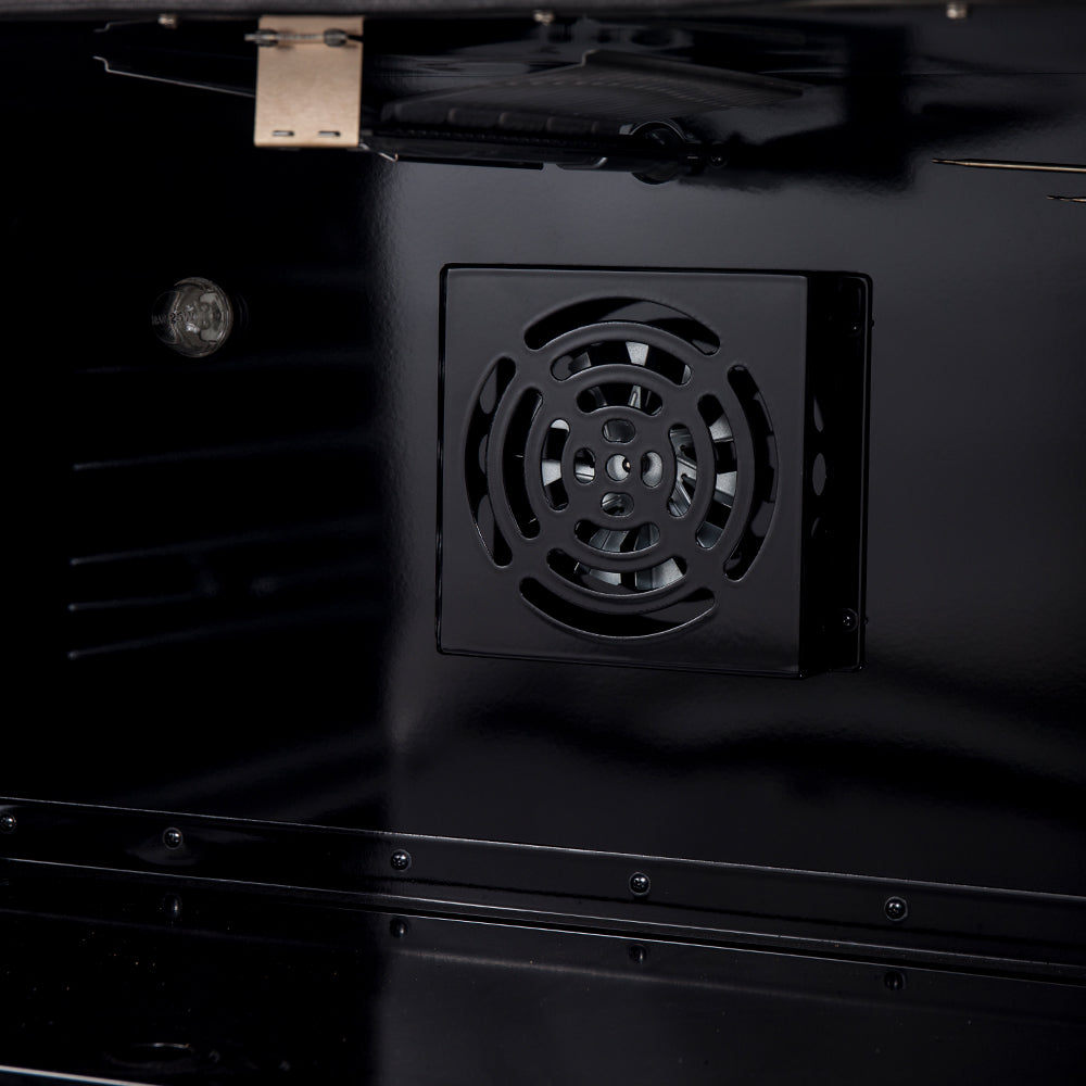 Gas range oven bottom access vent with circular fan-like grille, dark interior view