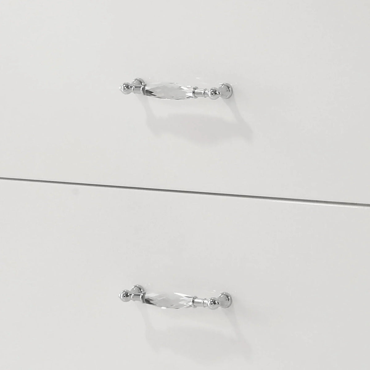 Close-up of chrome handles on the upper and lower drawers of a white nightstand.